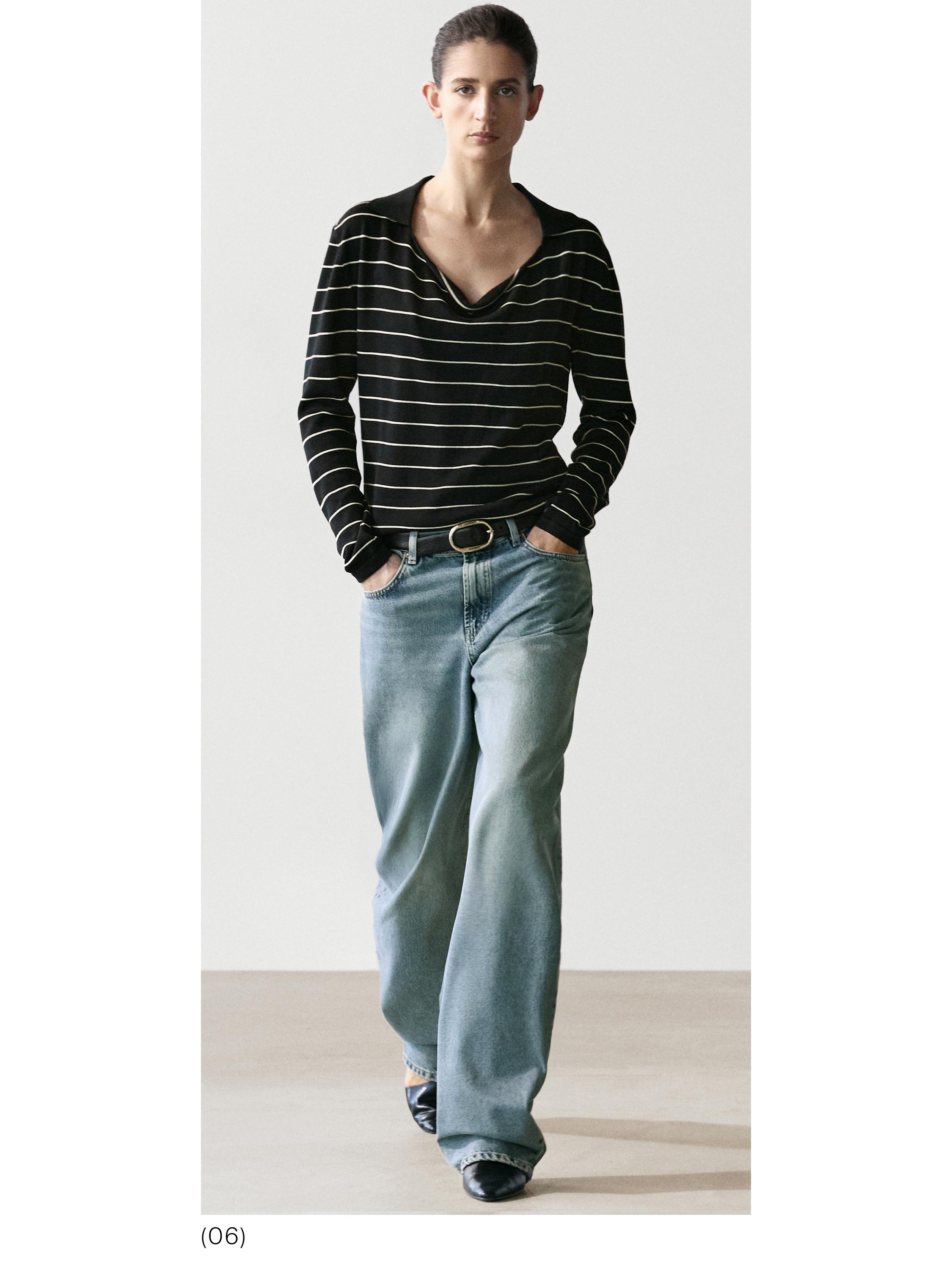 Conjunto de jersey negro con rayas blancas y jeans azul claro de pierna ancha, con bolsillos laterales.