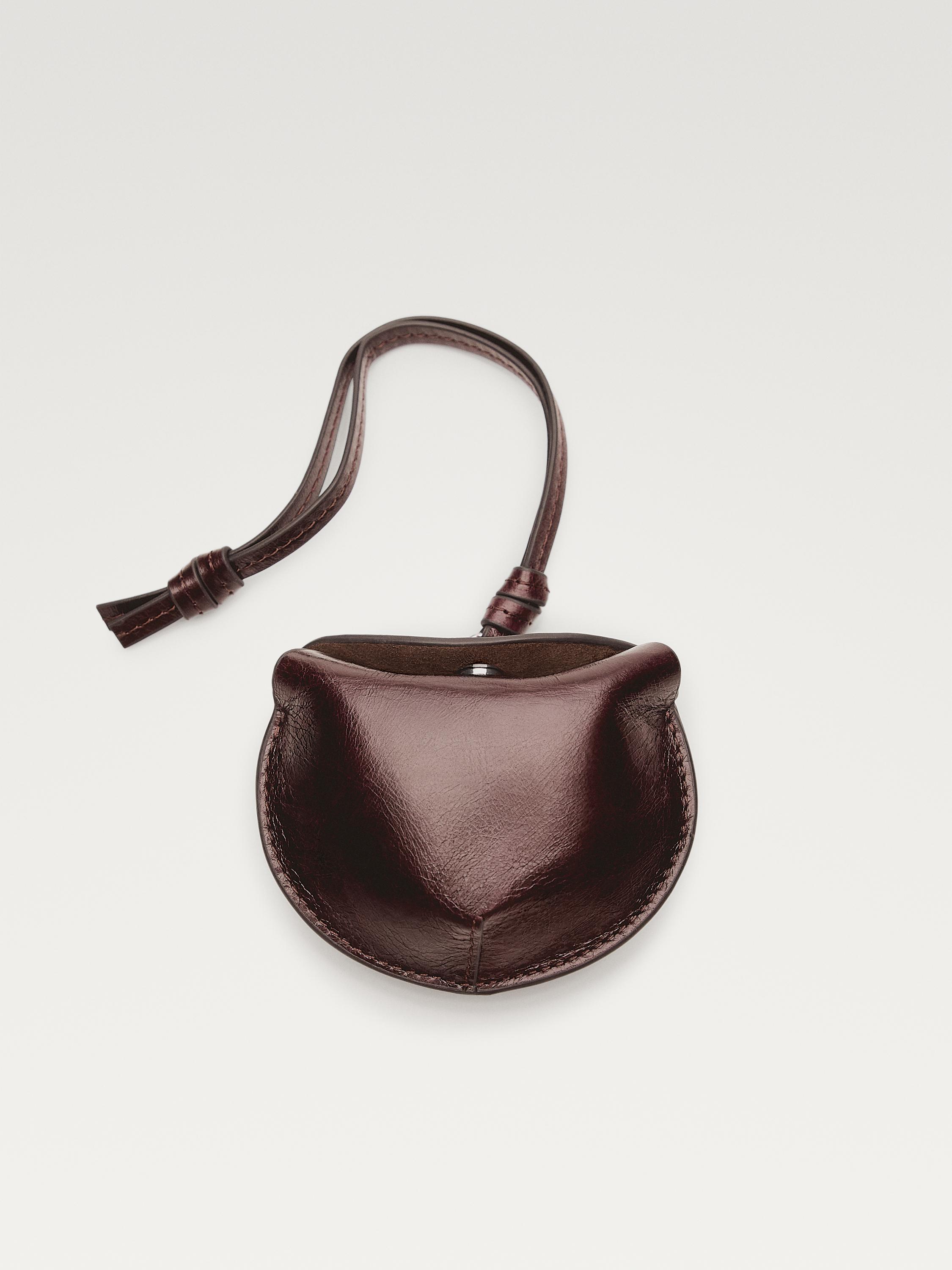 Vista frontal de funda plegable per a AirPods marró fosc amb tancament de botó i corretja ajustable.