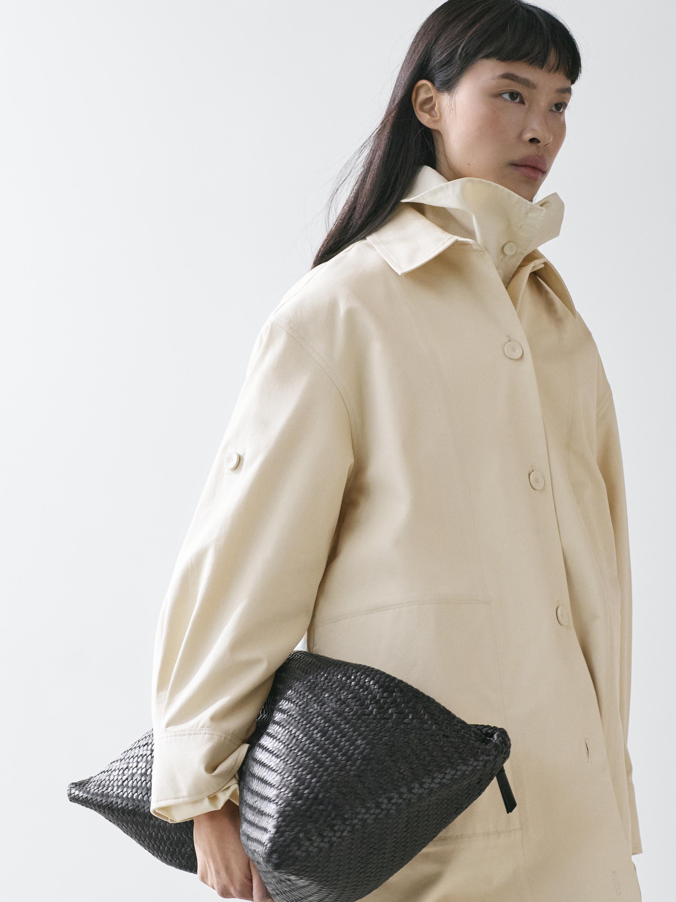 plaintext Medium shot of a light yellow trench coat with roll-up sleeves and visible buttons.