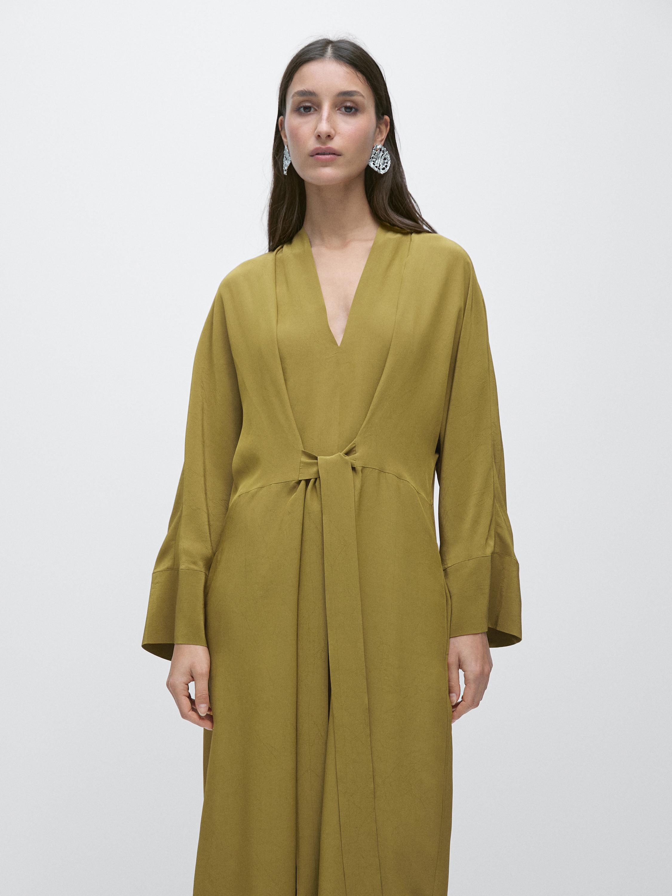 لقطة متوسطة لفستان أخضر طويل بياقة على شكل V وربطة أمامية.