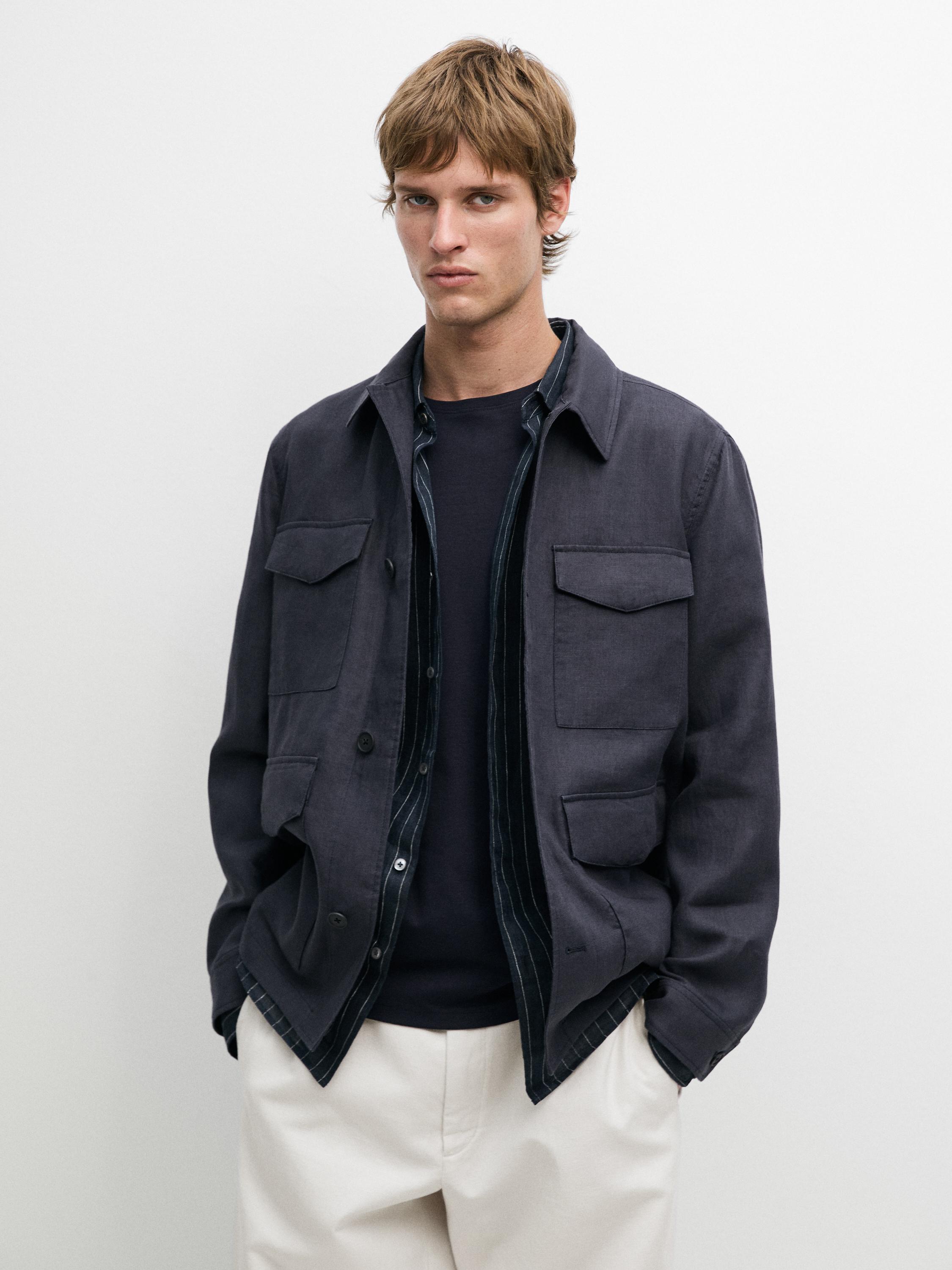 Conjunto de casaco azul com bolsos frontais, camisa às riscas e calças claras.