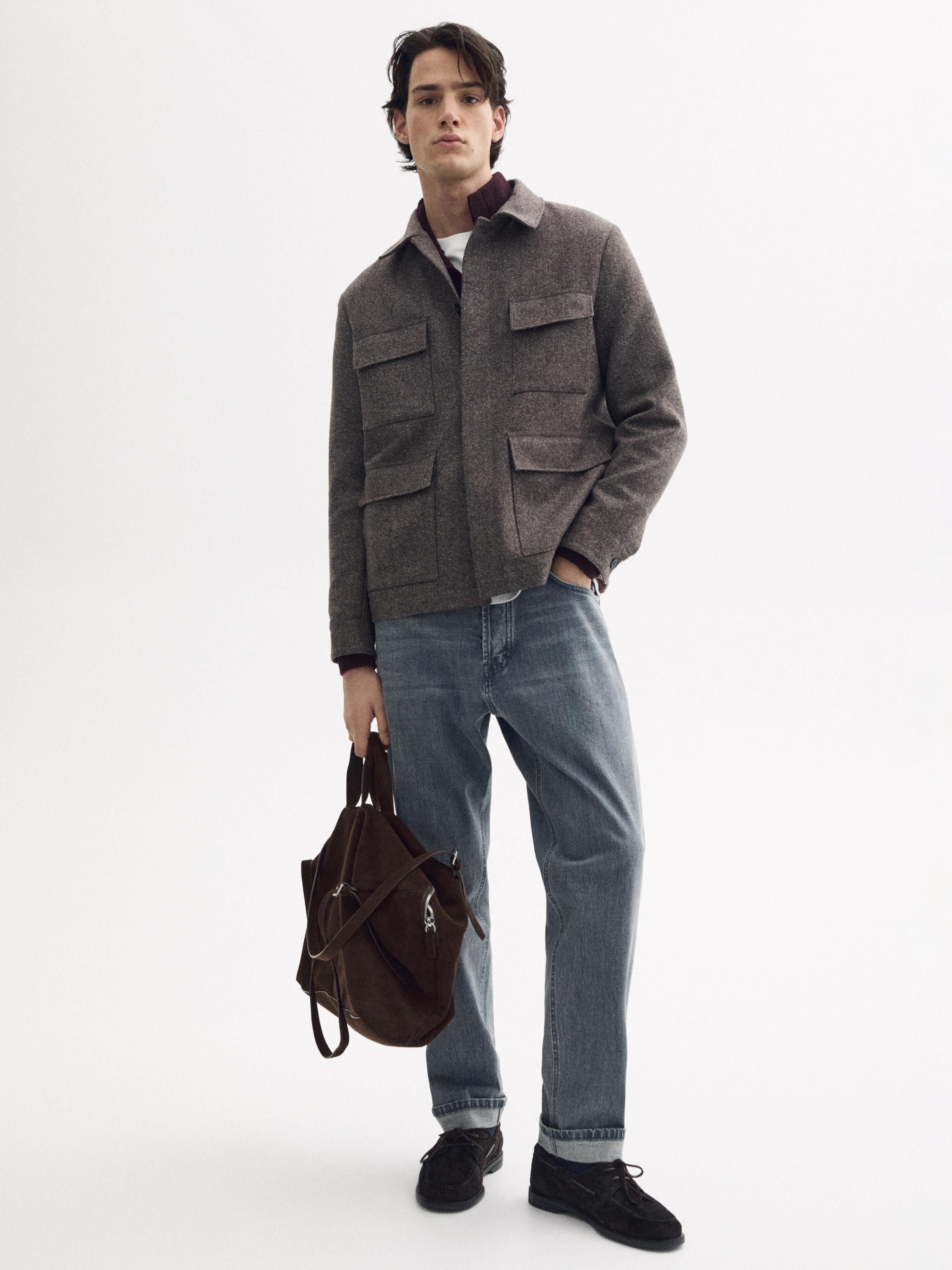 앞주머니가 있는 갈색 재킷과 그레이 셀비지 핏 진 코디. 갈색 가방과 어두운 색 신발을 착용.