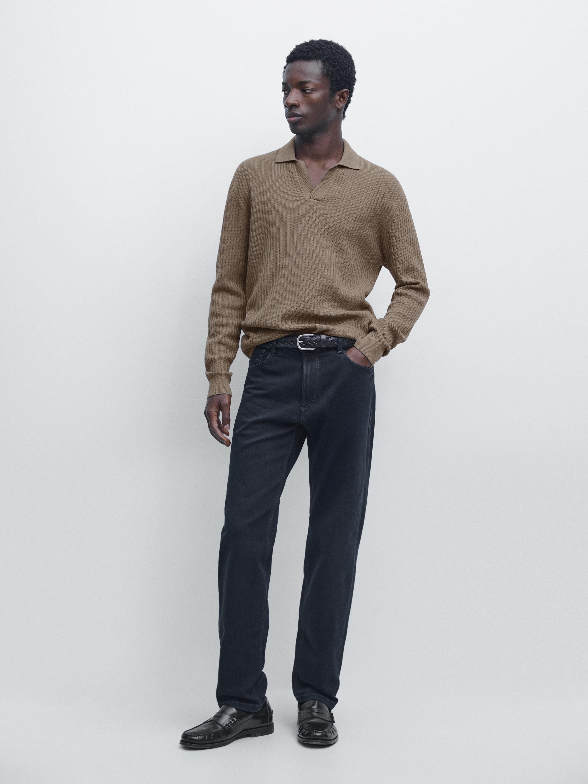 Súprava hnedého pleteného svetra s otvoreným golierom a modrých slim fit džínsov, čierny opasok a čierne mokasíny.