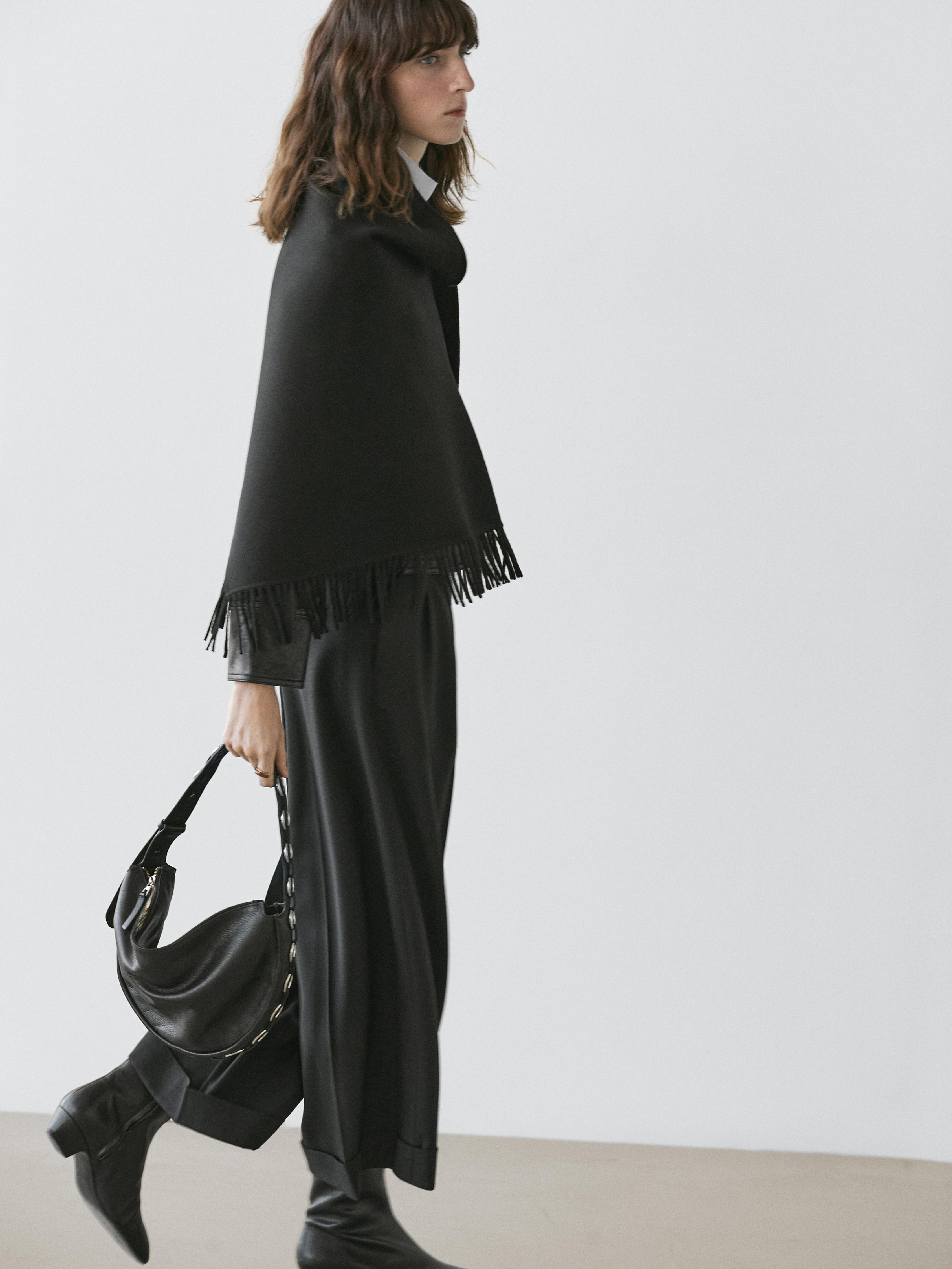 Ensemble composé d'une écharpe noire à franges, d'un pantalon ample noir et de bottes noires à talon bas.