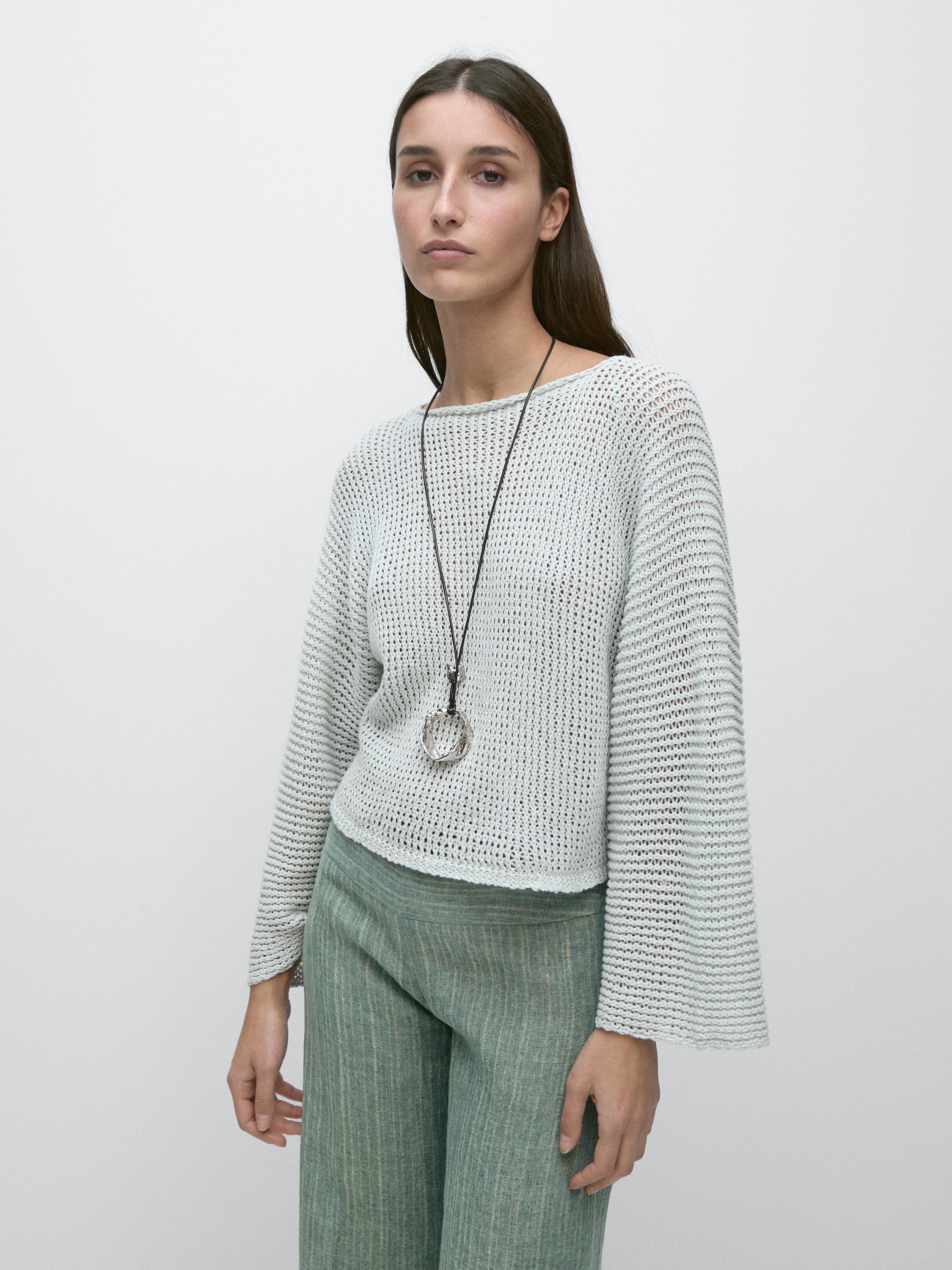 Conjunto de suéter de punto calado verde claro con mangas largas y pantalones verdes de rayas verticales.