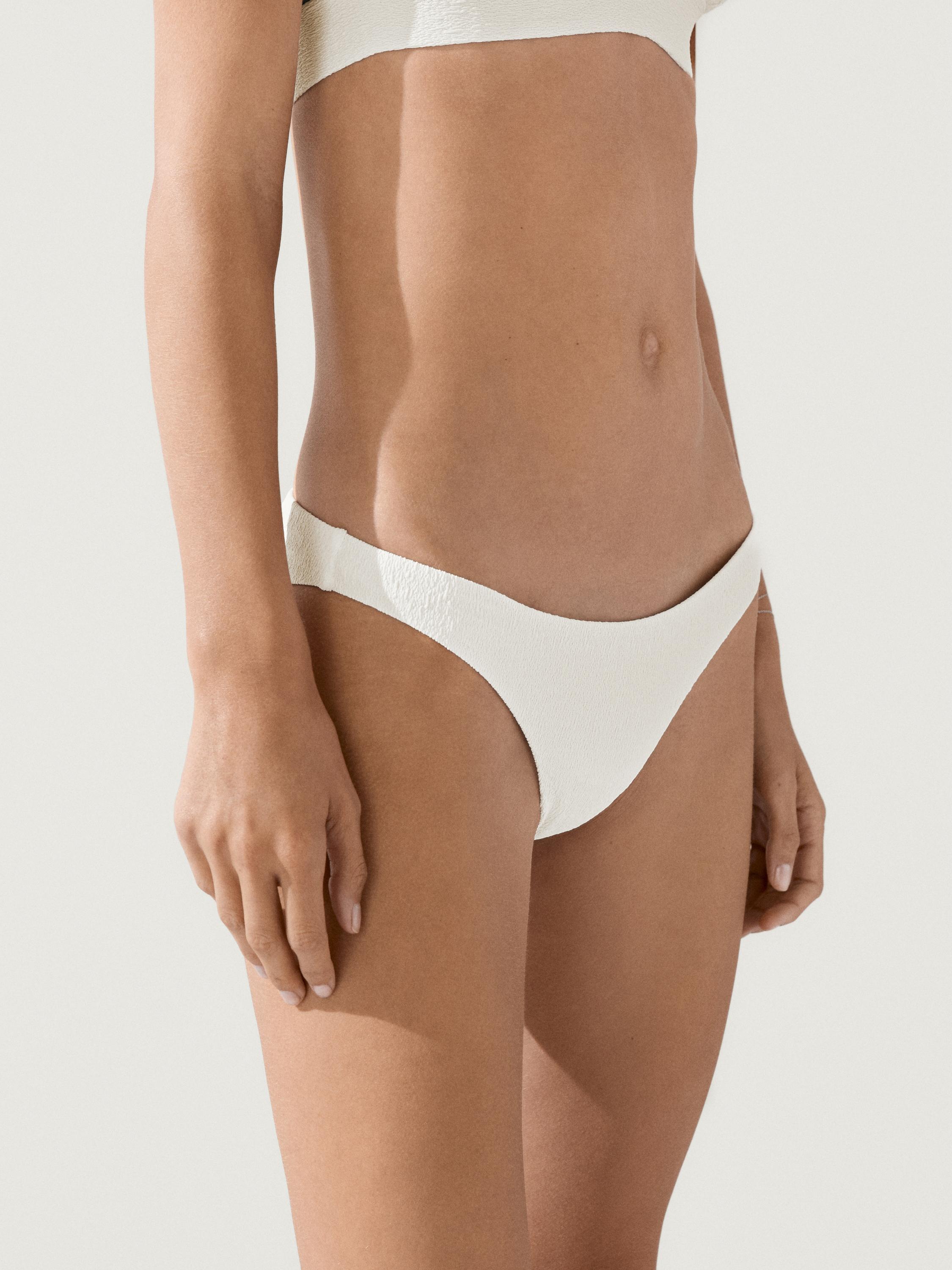 plaintext Dokulu, kirli beyaz bikini altının orta plan çekimi.