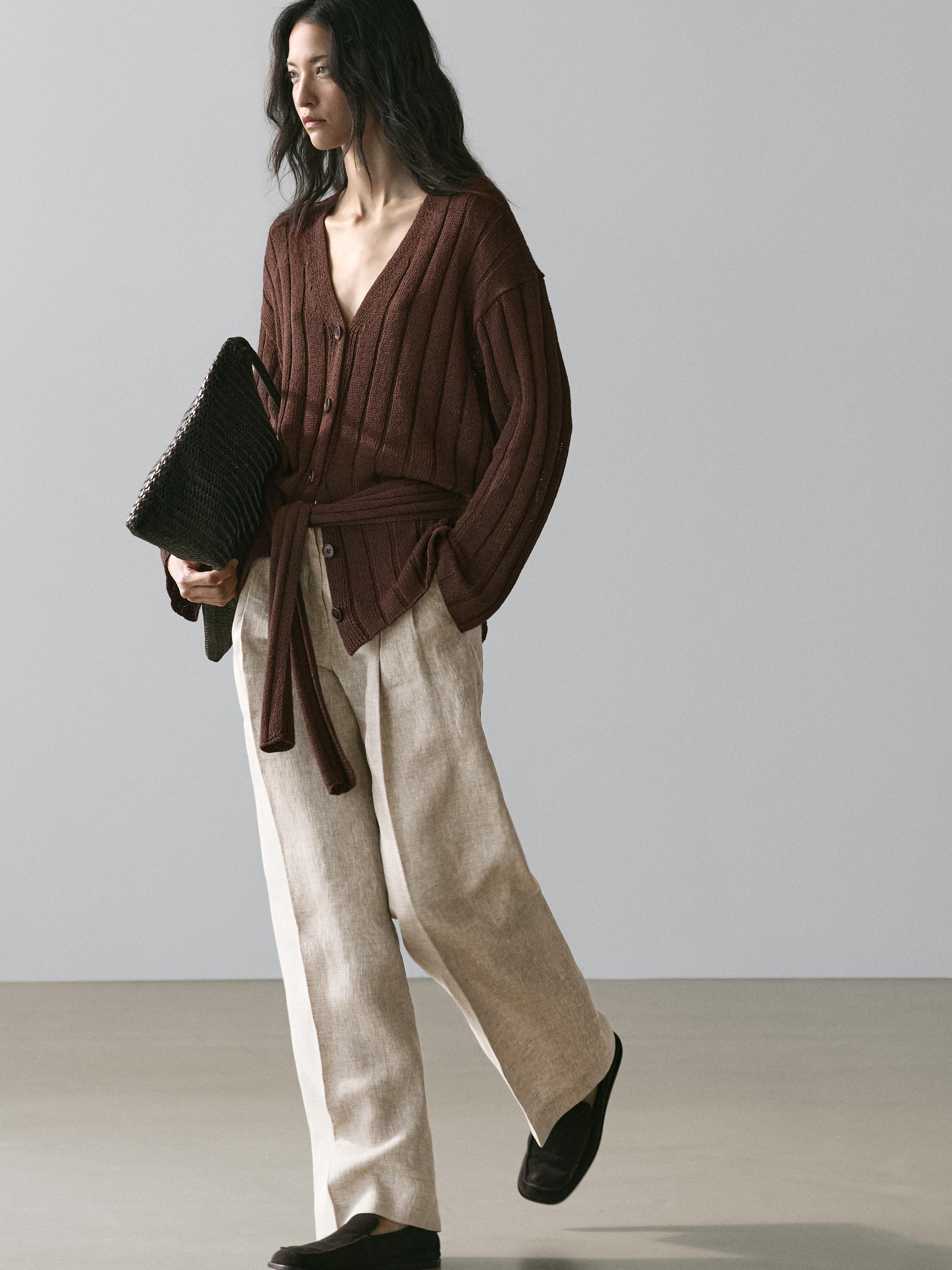 Tugmachali va kamarlik jigarrang kardigan to'plami, keng oyoqli bej shimlar va qora tufli.