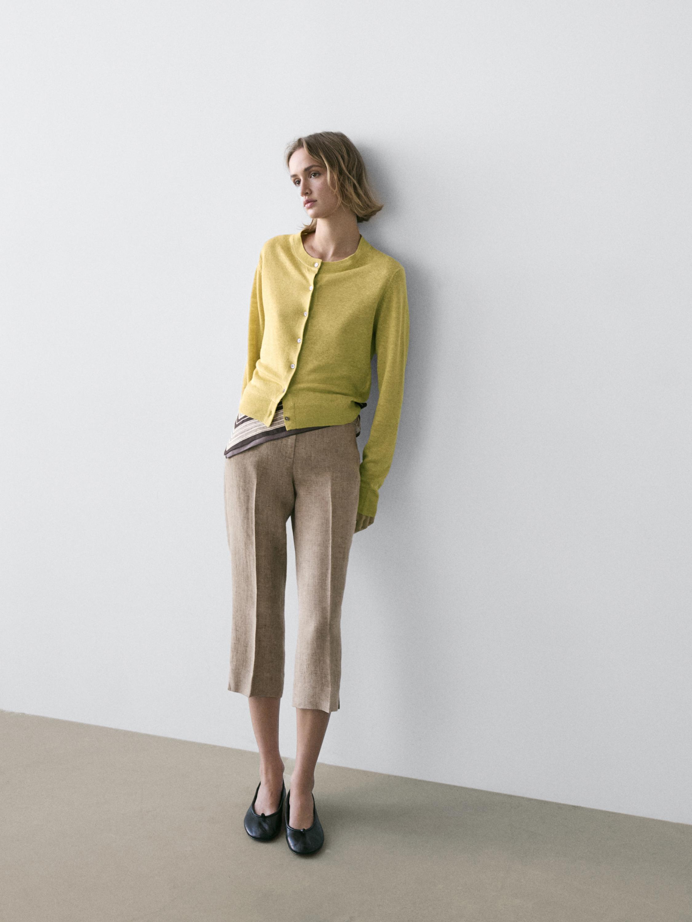 Zestaw: limonkowy kardigan zapinany na guziki i beżowe spodnie z prostymi nogawkami do połowy łydki.