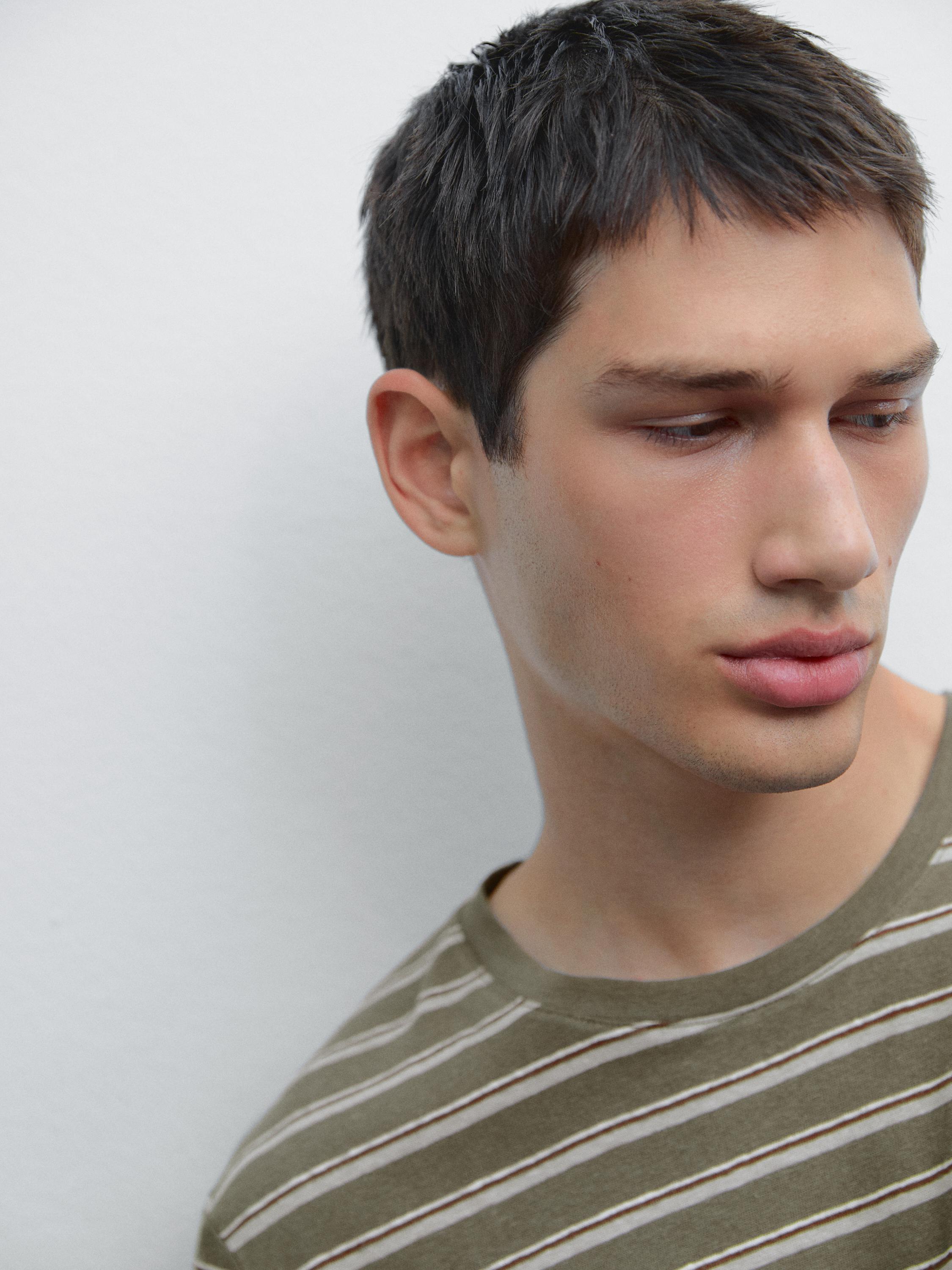 Gros plan d'un t-shirt à rayures horizontales vert olive et blanches.