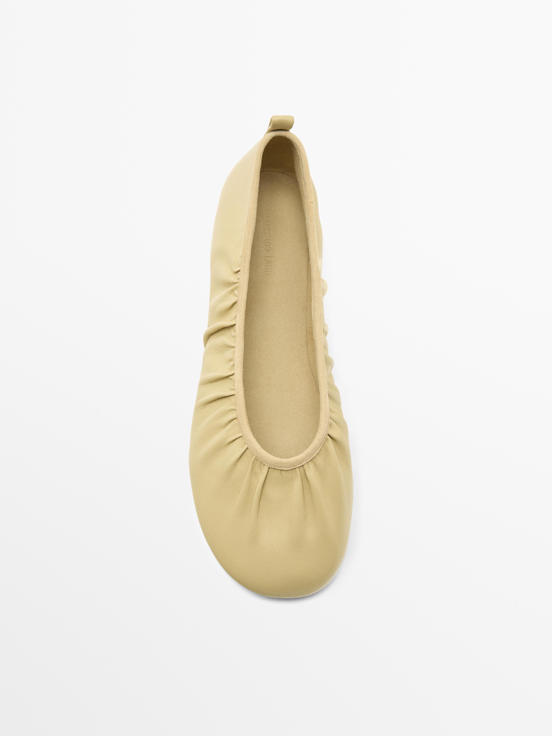 Widok z góry beżowych balerin marszczonych z zaokrągloną krawędzią i tylnym językiem.