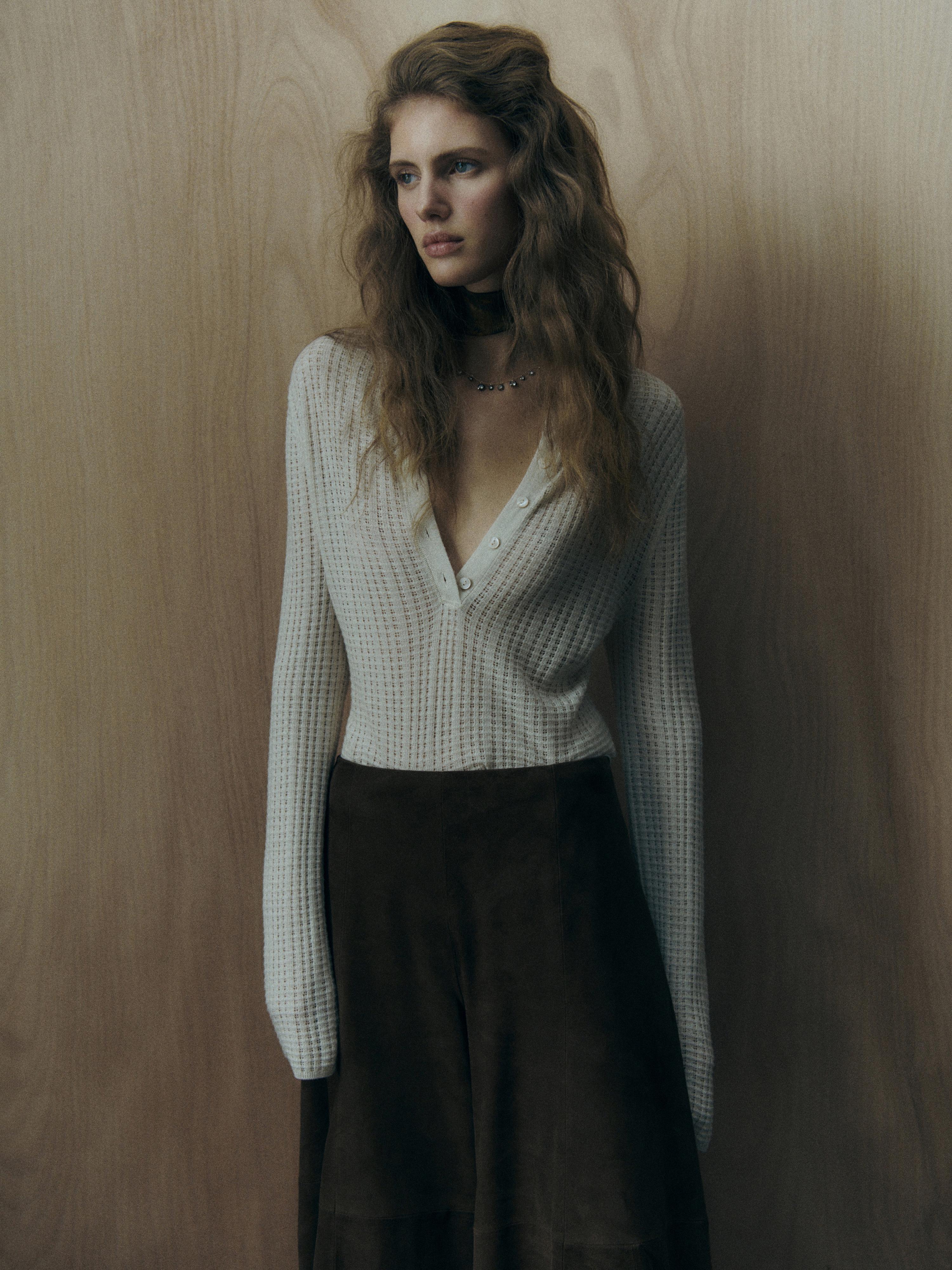 Ensemble composé d'un chemisier blanc en maille avec encolure en V et boutons, et d'une longue jupe marron.