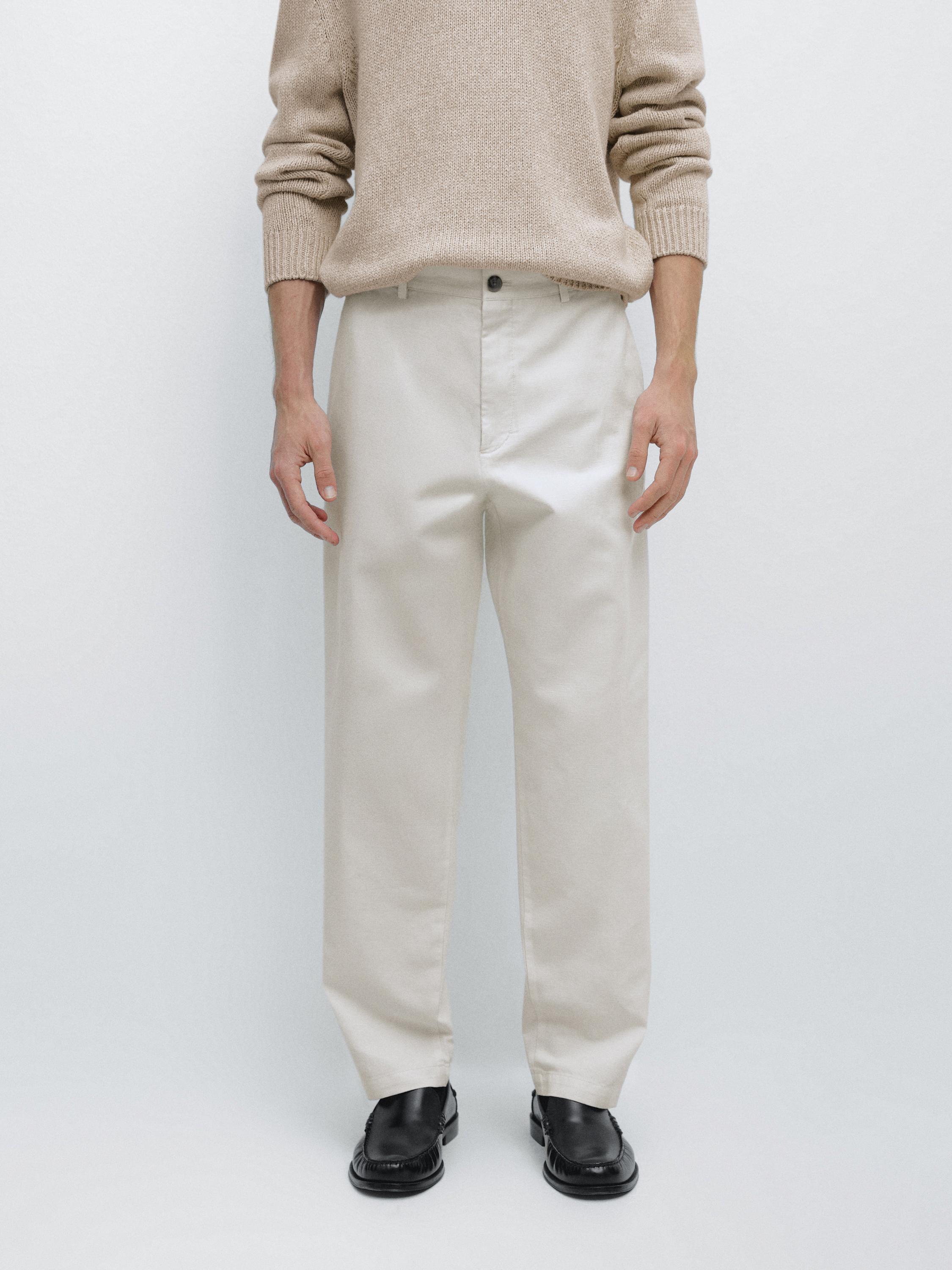 Pants set with side pockets and button closure, paired with a beige sweater and black shoes.