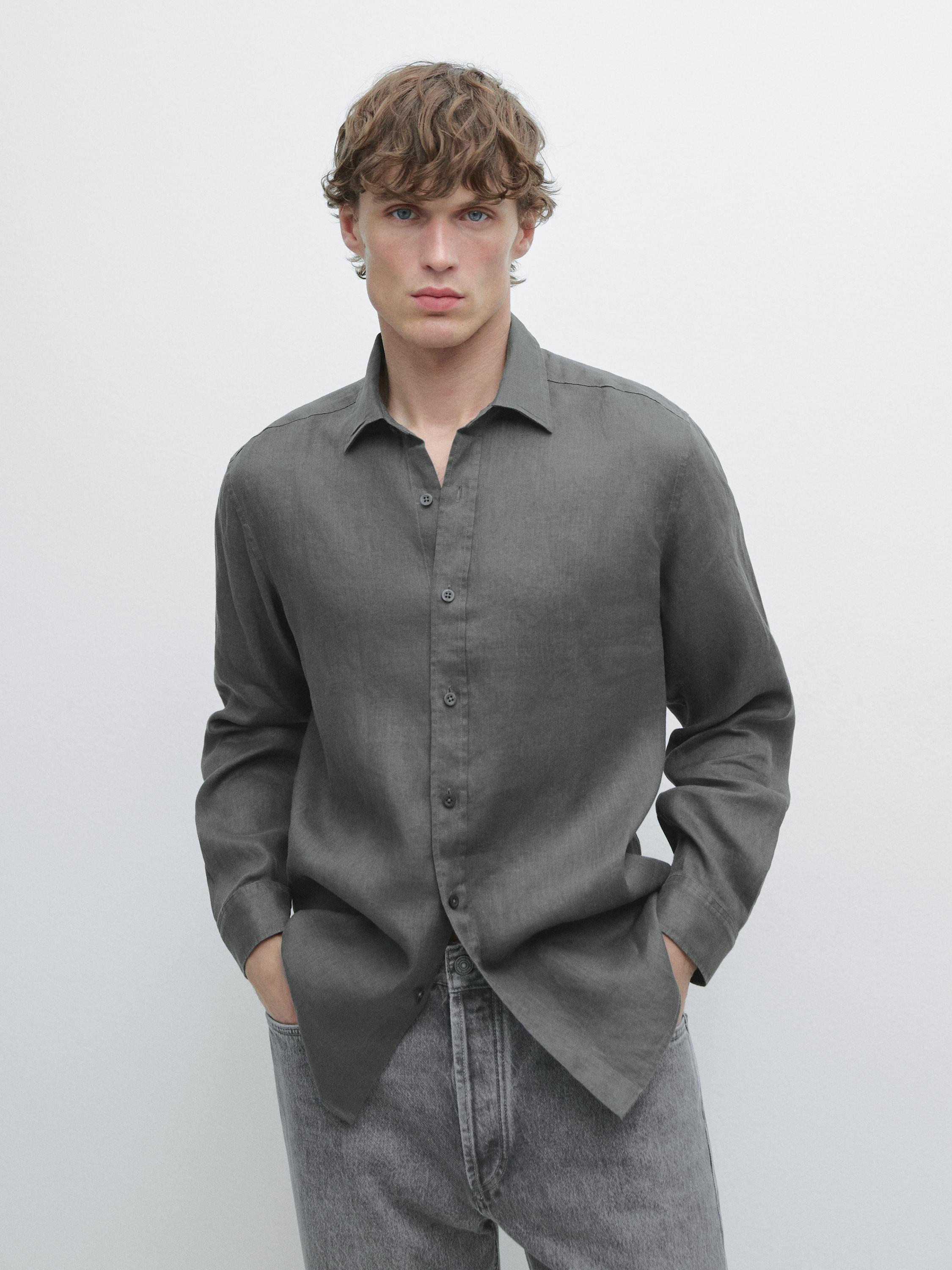 Dunkelgrünes Langarmhemd mit Knöpfen und graue Hose.