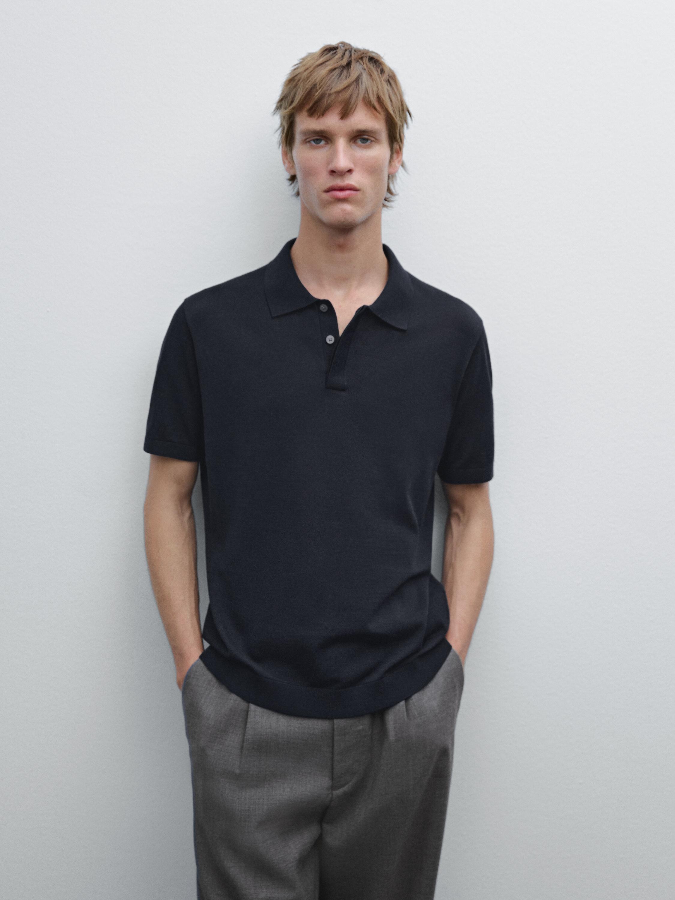 Ensemble polo noir et pantalon gris avec poches latérales.