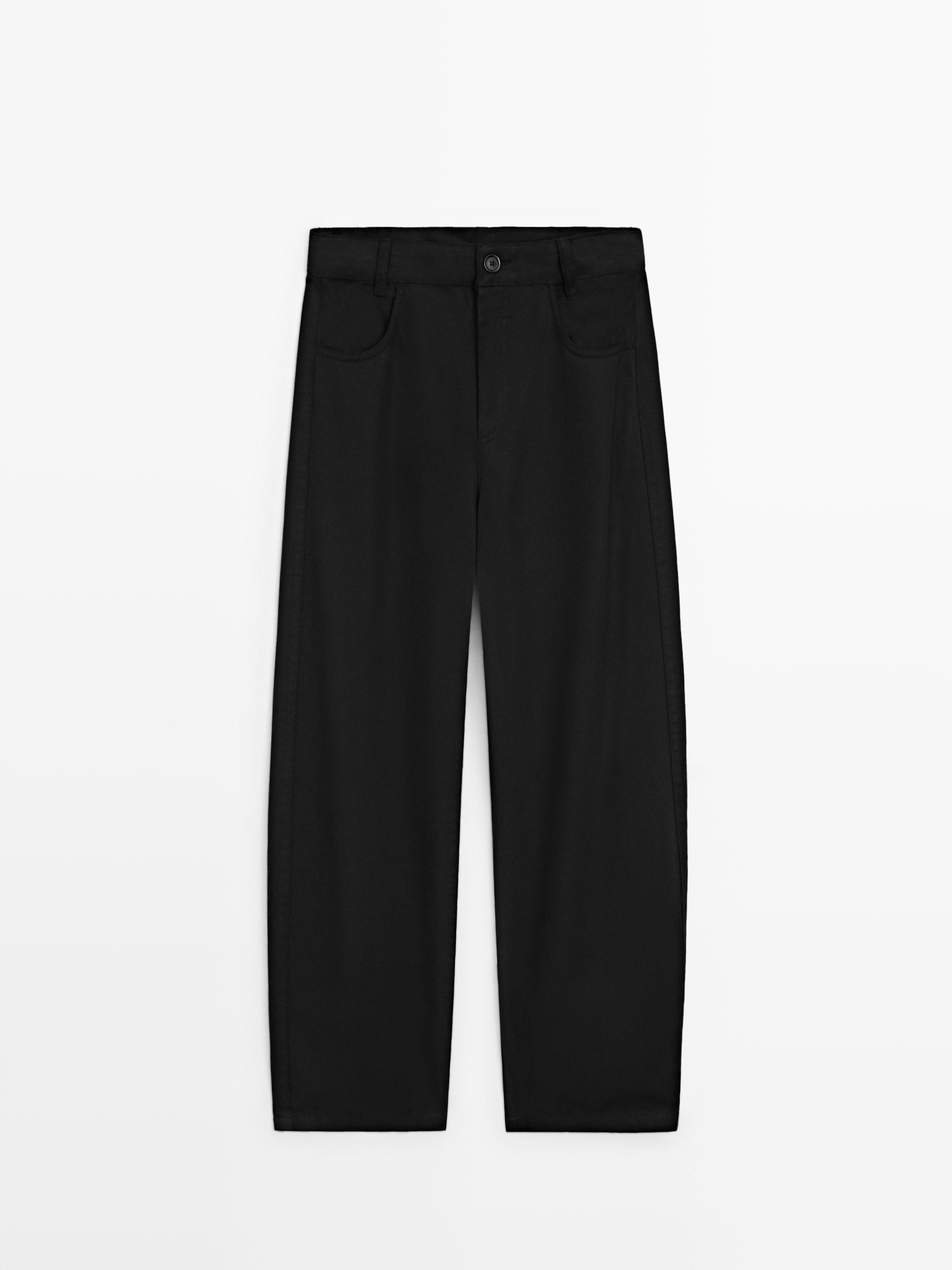 Vista frontale di pantaloni neri taglio barrel fit con tasche anteriori e passanti per cintura.