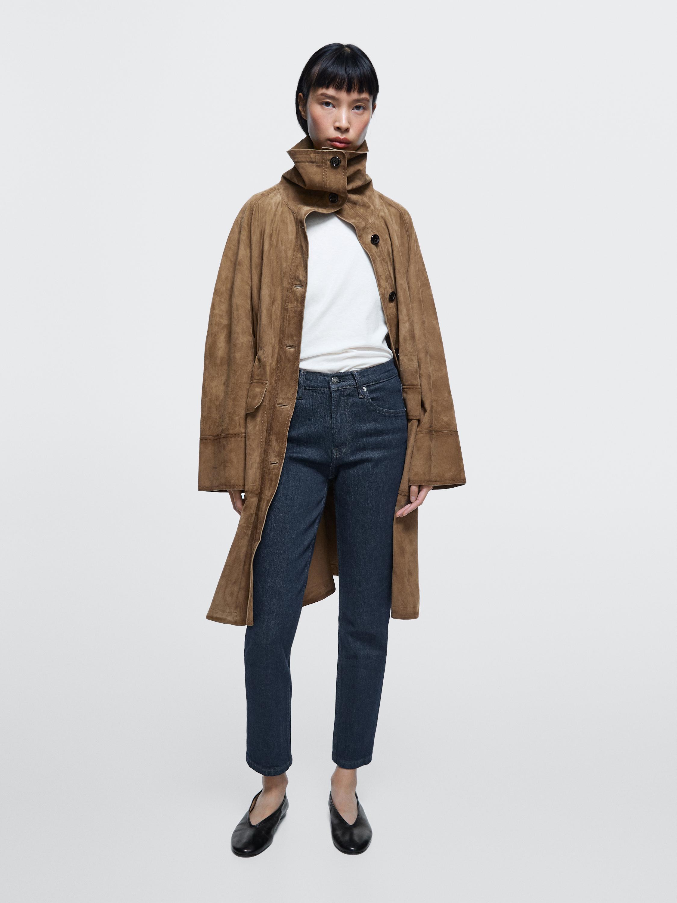 Brown high-neck button-up coat set, white t-shirt, dark blue slim-fit jeans, and black shoes.