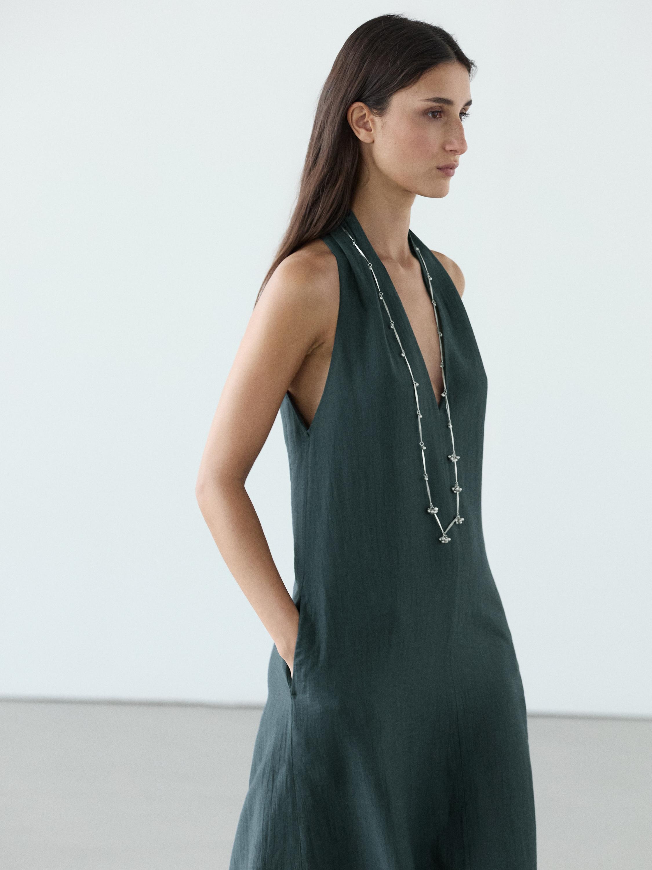 Mid-shot of a dark blue midi dress with a V-neckline and side pockets.