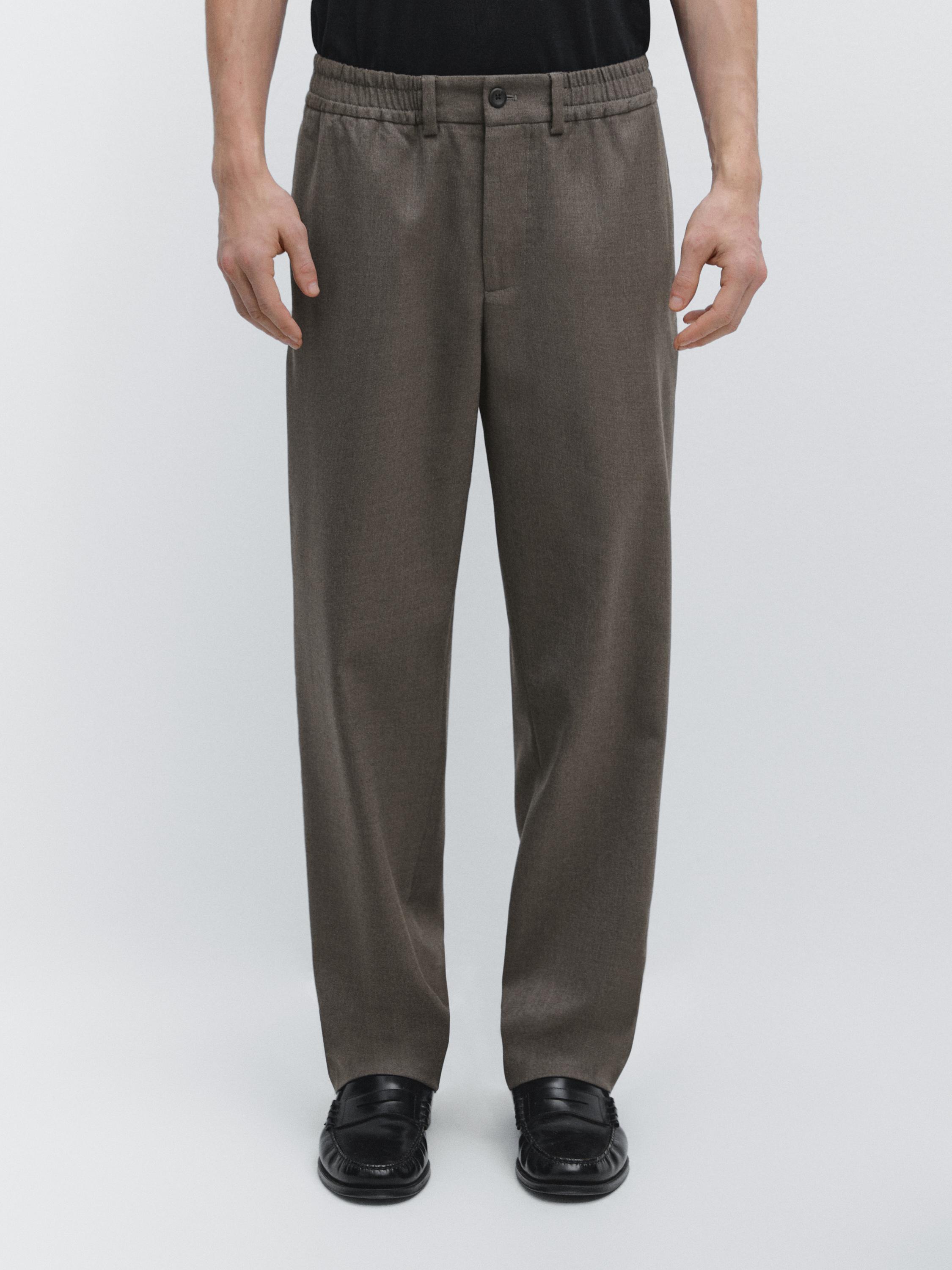 Mittelbeiges Hosen-Set mit elastischem Bund, Knopfverschluss vorne und seitlichen Taschen.