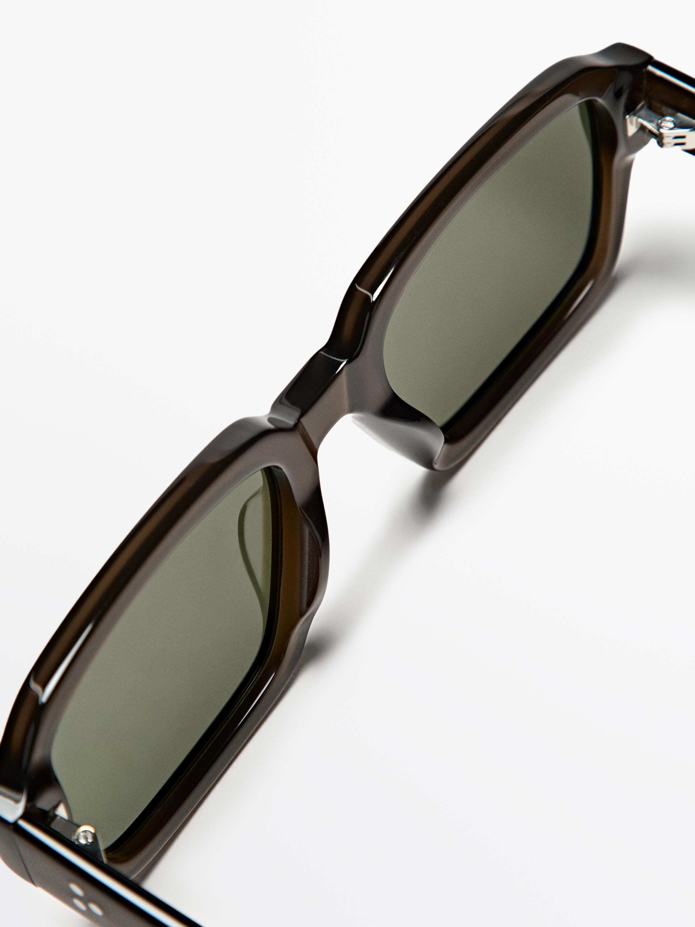 Kalın kahverengi çerçeveli ve yeşil camlı güneş gözlüğü detayı.