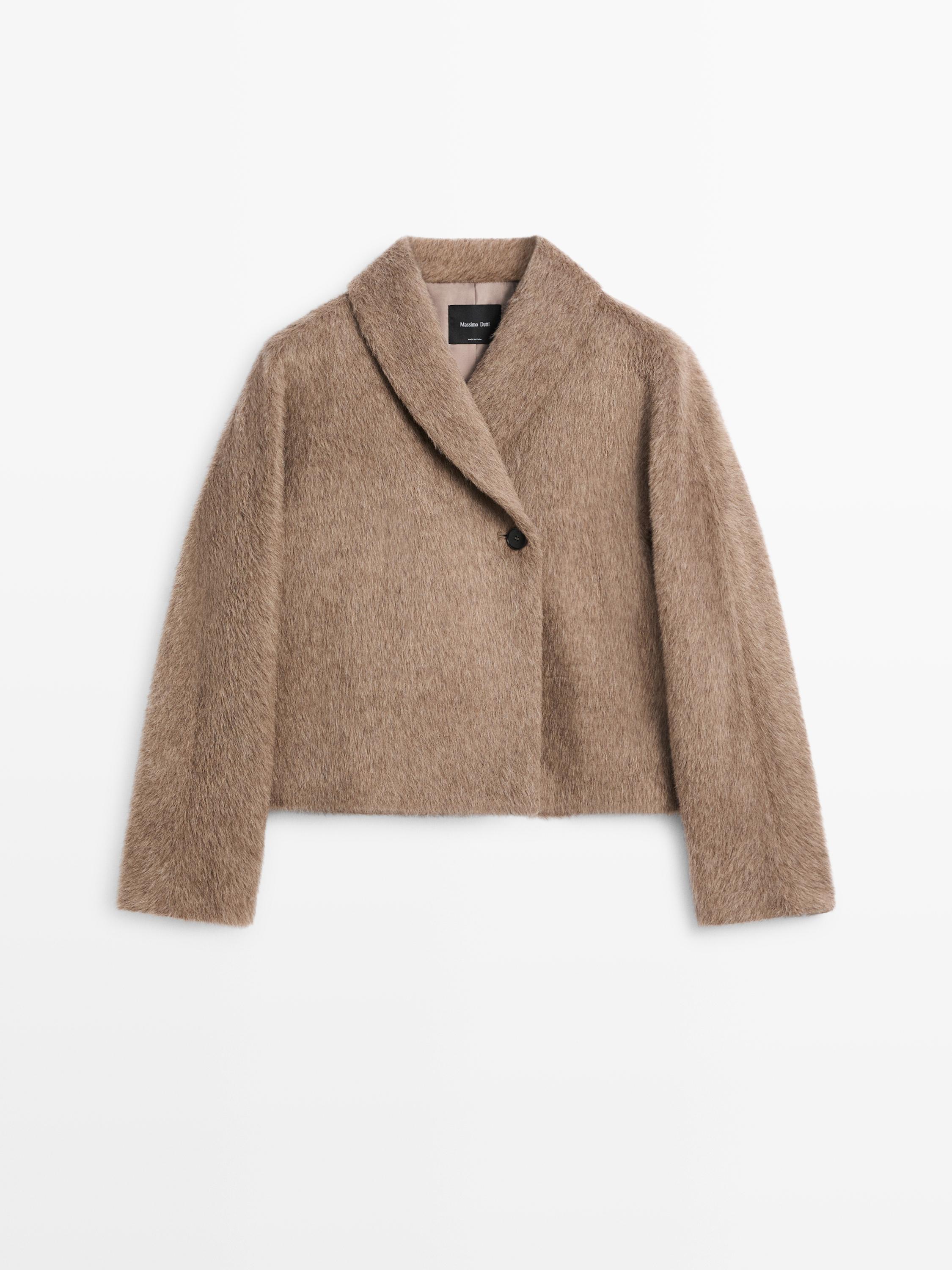 มุมมองด้านหน้าของเสื้อแจ็คเก็ตครอปแบบป้ายสีกากีอมน้ำตาล มีคอปกกว้างและกระดุมที่มองเห็นได้หนึ่งเม็ด