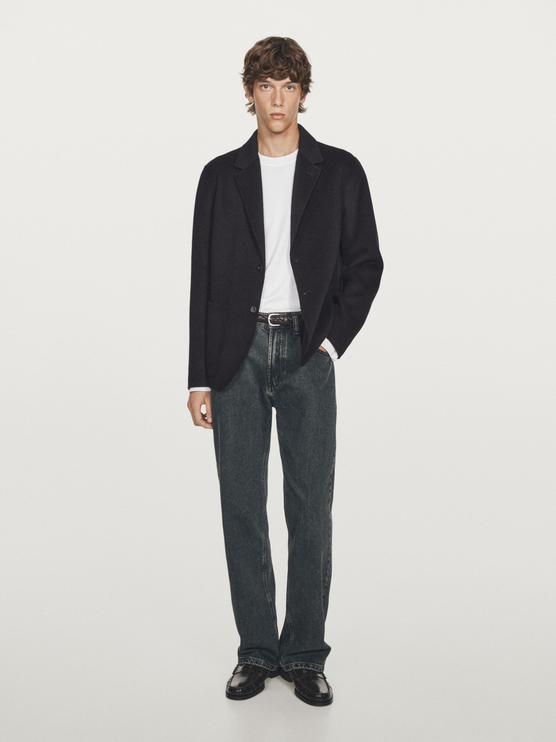 Conxunto de americana azul mariño con lapela e botón, camiseta branca, vaqueiros escuros e zapatos negros.