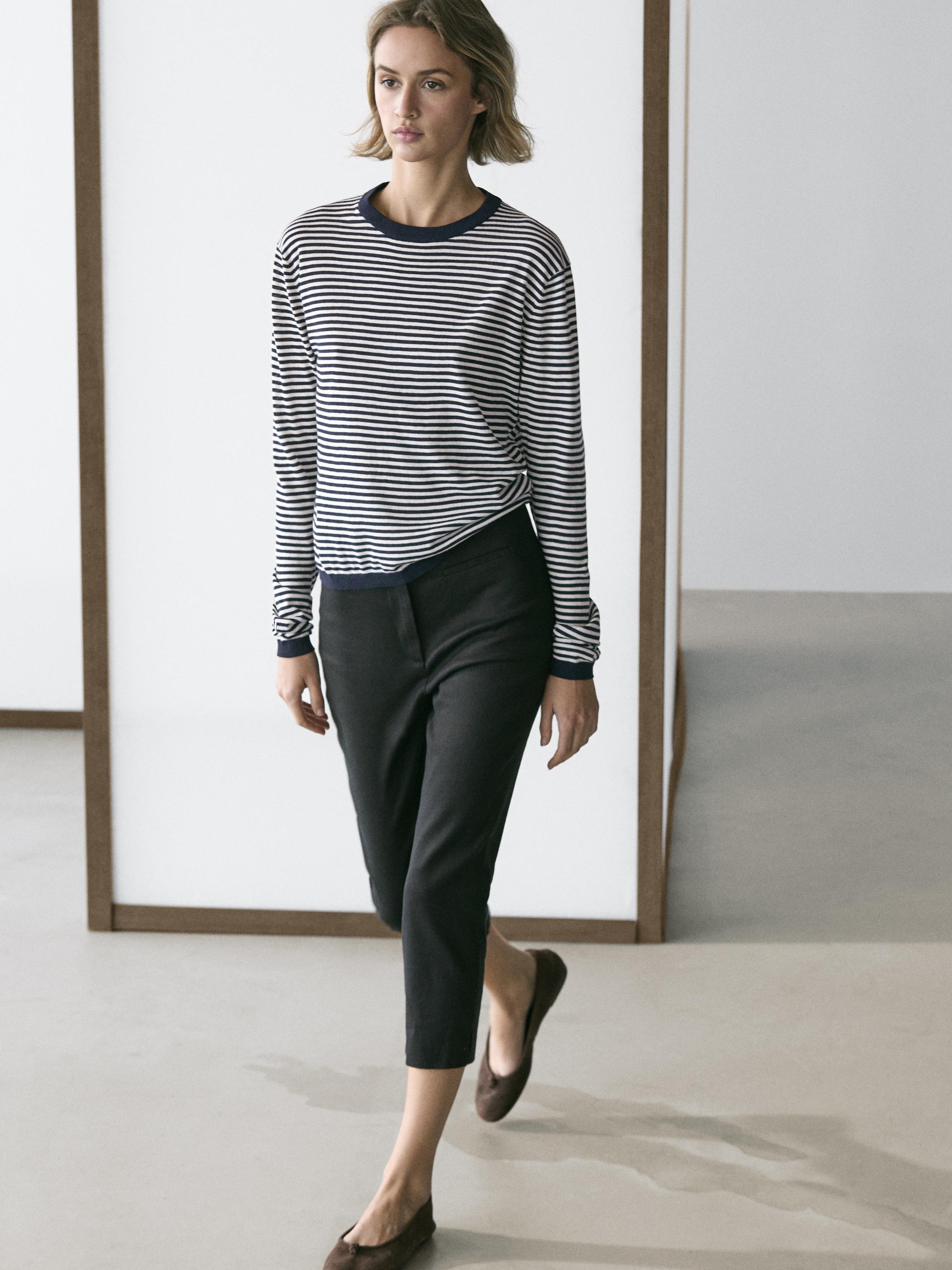 Conjunto de jersey de rayas azul marino y blanco con pantalones negros de corte recto y largo al tobillo.