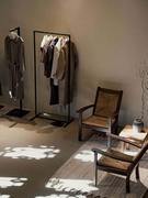 Coin douillet avec des chaises en bois, un porte-manteau avec des vêtements élégants et une lumière douce et tamisée. Décoration minimaliste et moderne.