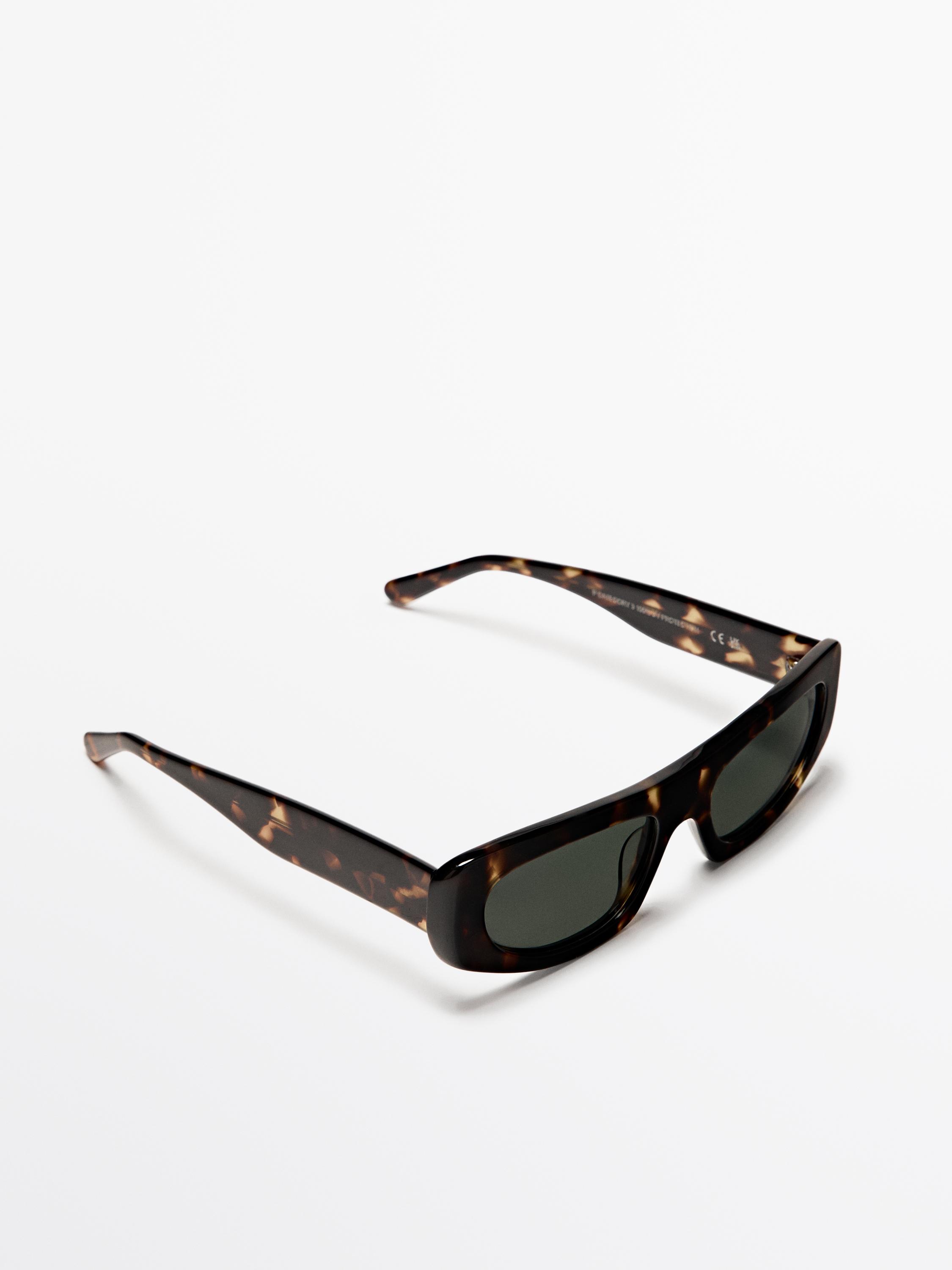 Lunettes de soleil ovales marron avec monture écaille de tortue et verres foncés.