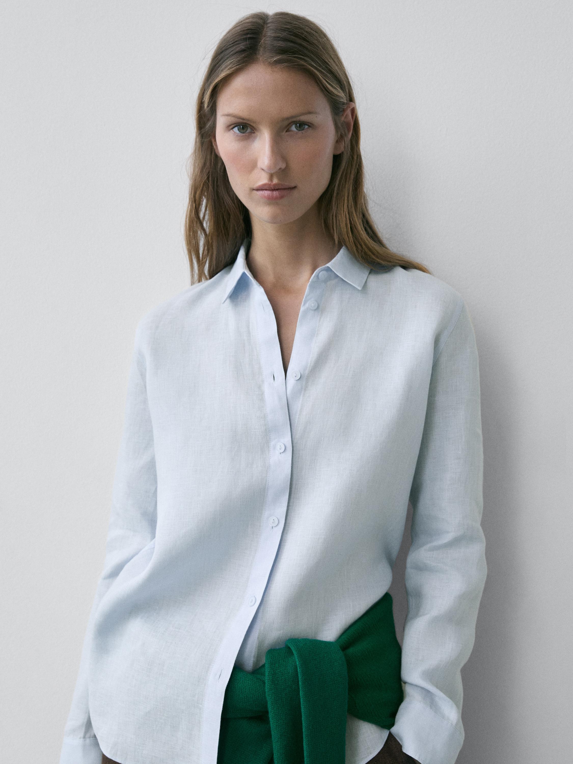 Light blue flowy shirt set with front buttons and classic collar, green sweater tied at the waist.