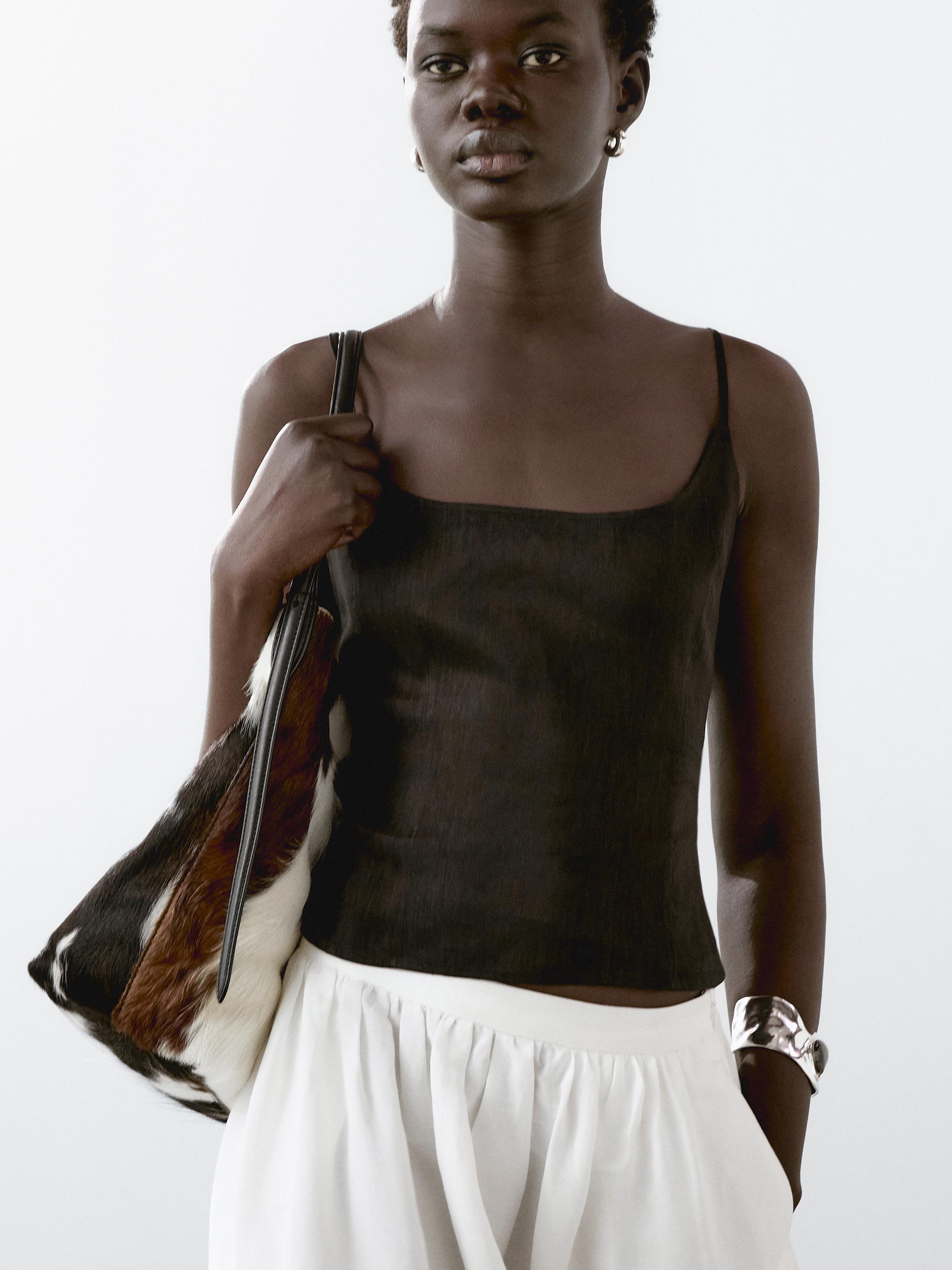 Plano medio de top negro de tirantes finos y falda blanca.