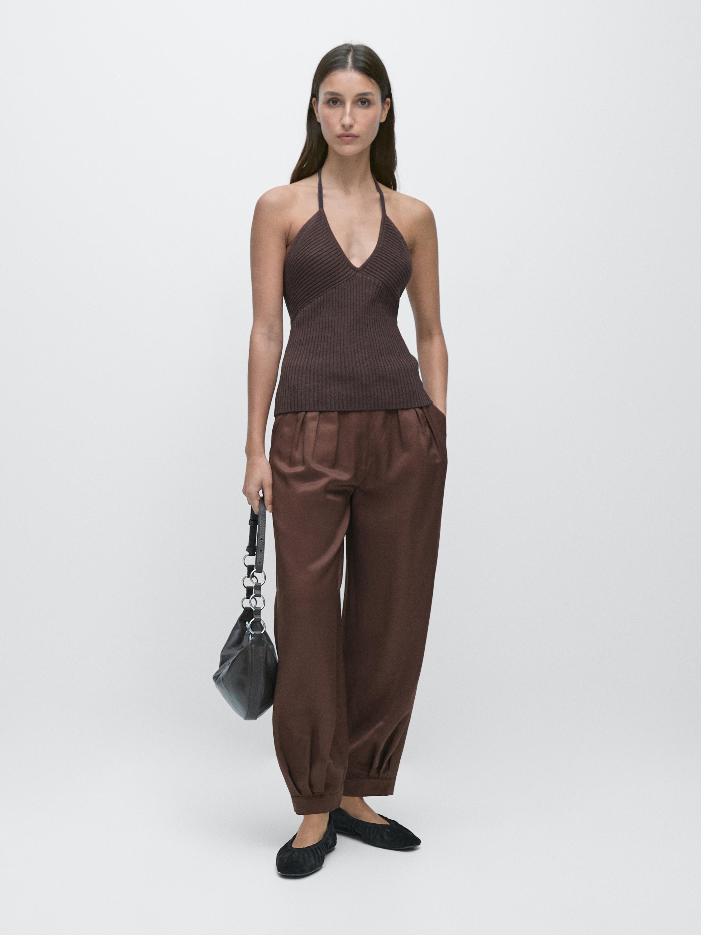 Eggplant top set with a backless design and loose brown pants with side pockets.