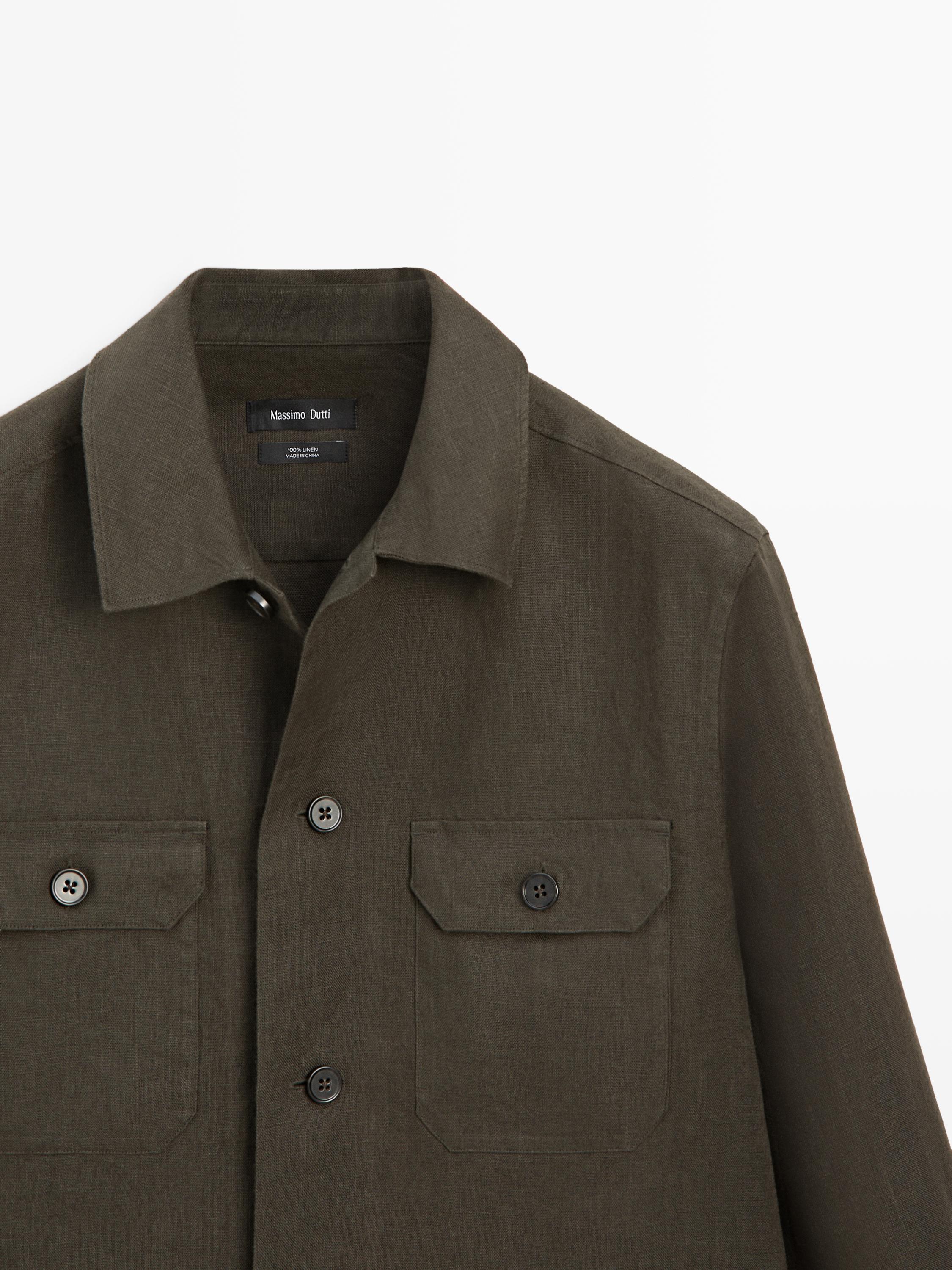 "Mid-shot of a dark green long-sleeved shirt with flap front pockets and visible buttons."
