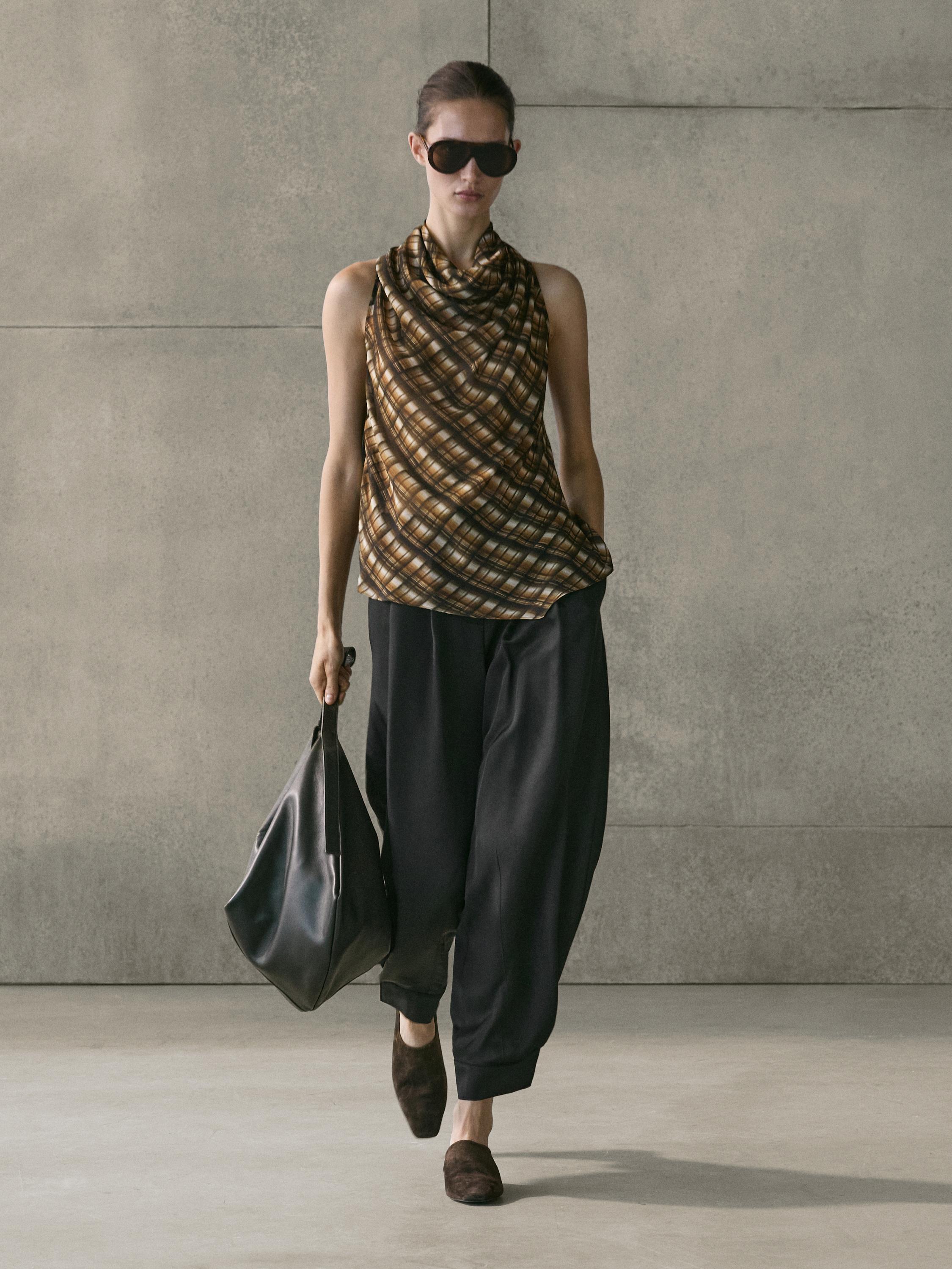 Set aus ärmelloser Bluse mit braunem Karomuster und lockerer schwarzer Hose.