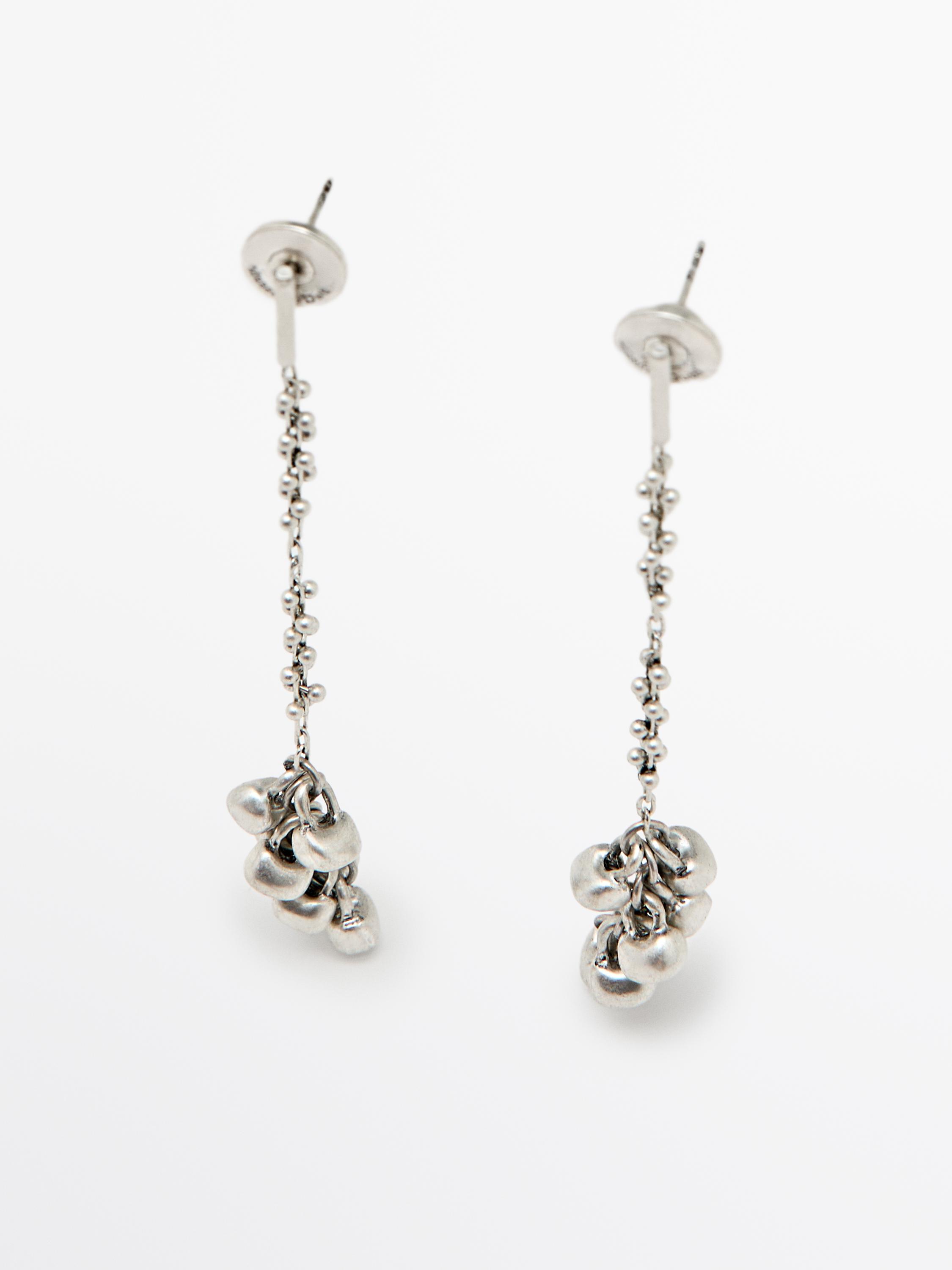 Lange, silberfarbene Ohrringe mit Gliederkette und traubenförmigen Anhängern am Ende.