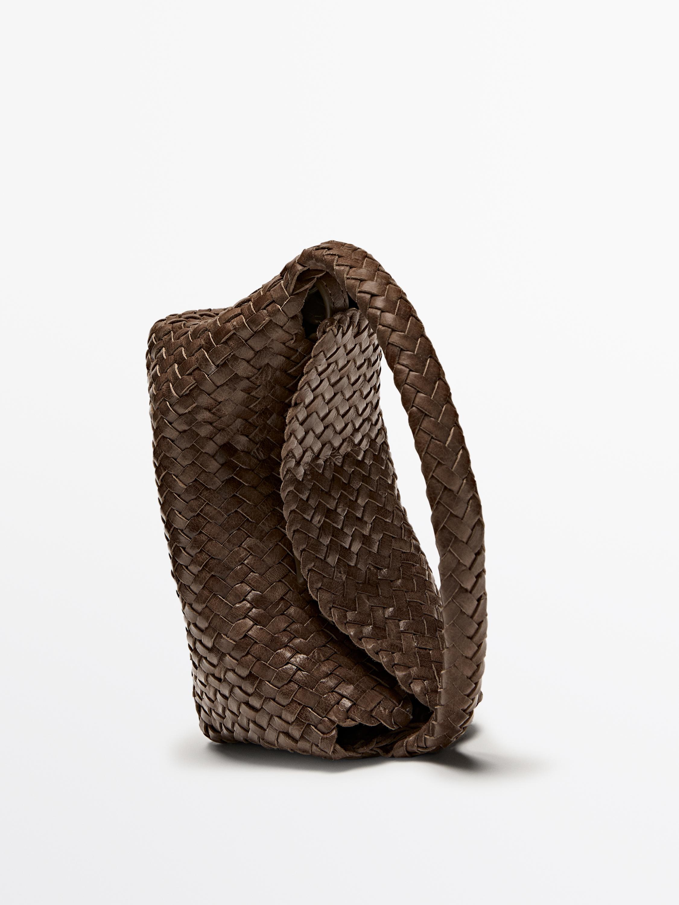 Vista lateral de bolso marrón tejido con asa trenzada.