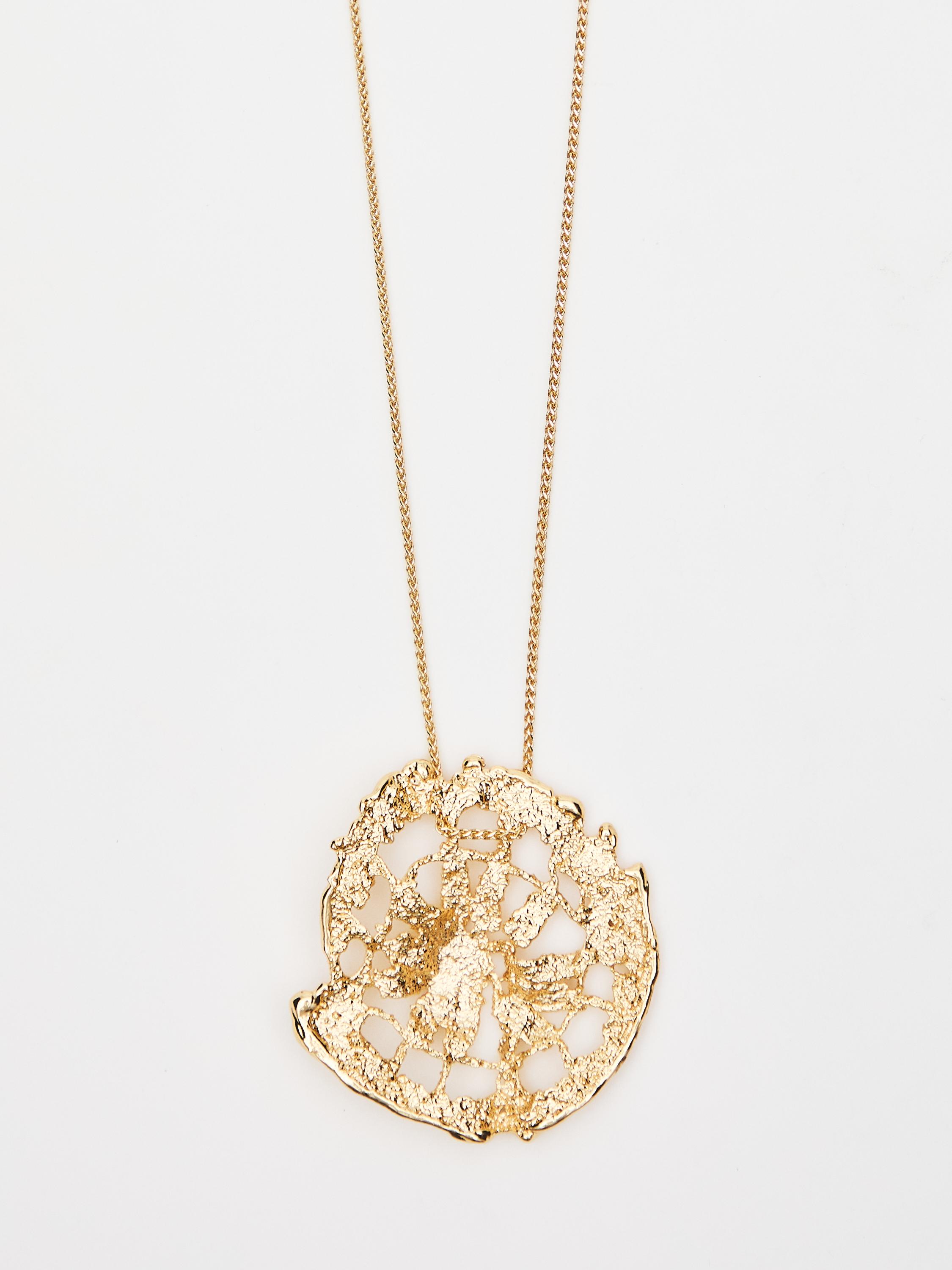 Collier doré avec pendentif circulaire au design abstrait et à la texture rugueuse.