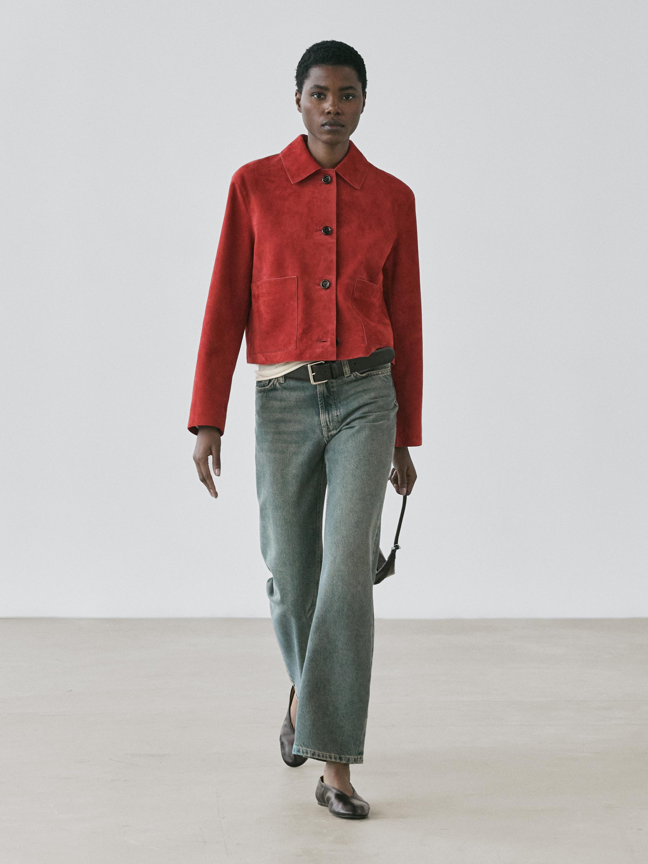 Conjunto de chaqueta roja corta con botones y bolsillos frontales, pantalones vaqueros rectos y zapatos planos marrones.