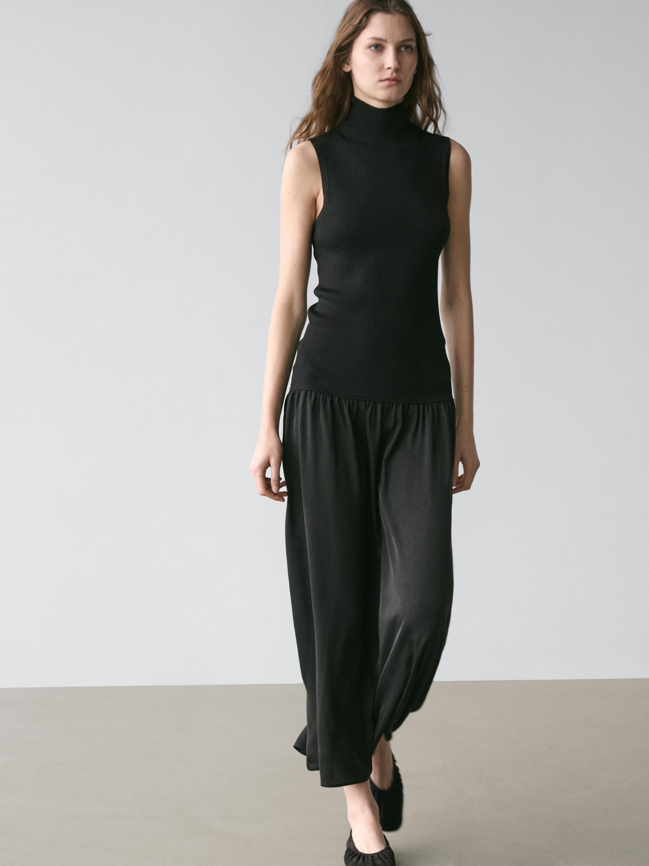 Crni komplet bez rukava s dolčevitom i širokom midi suknjom.