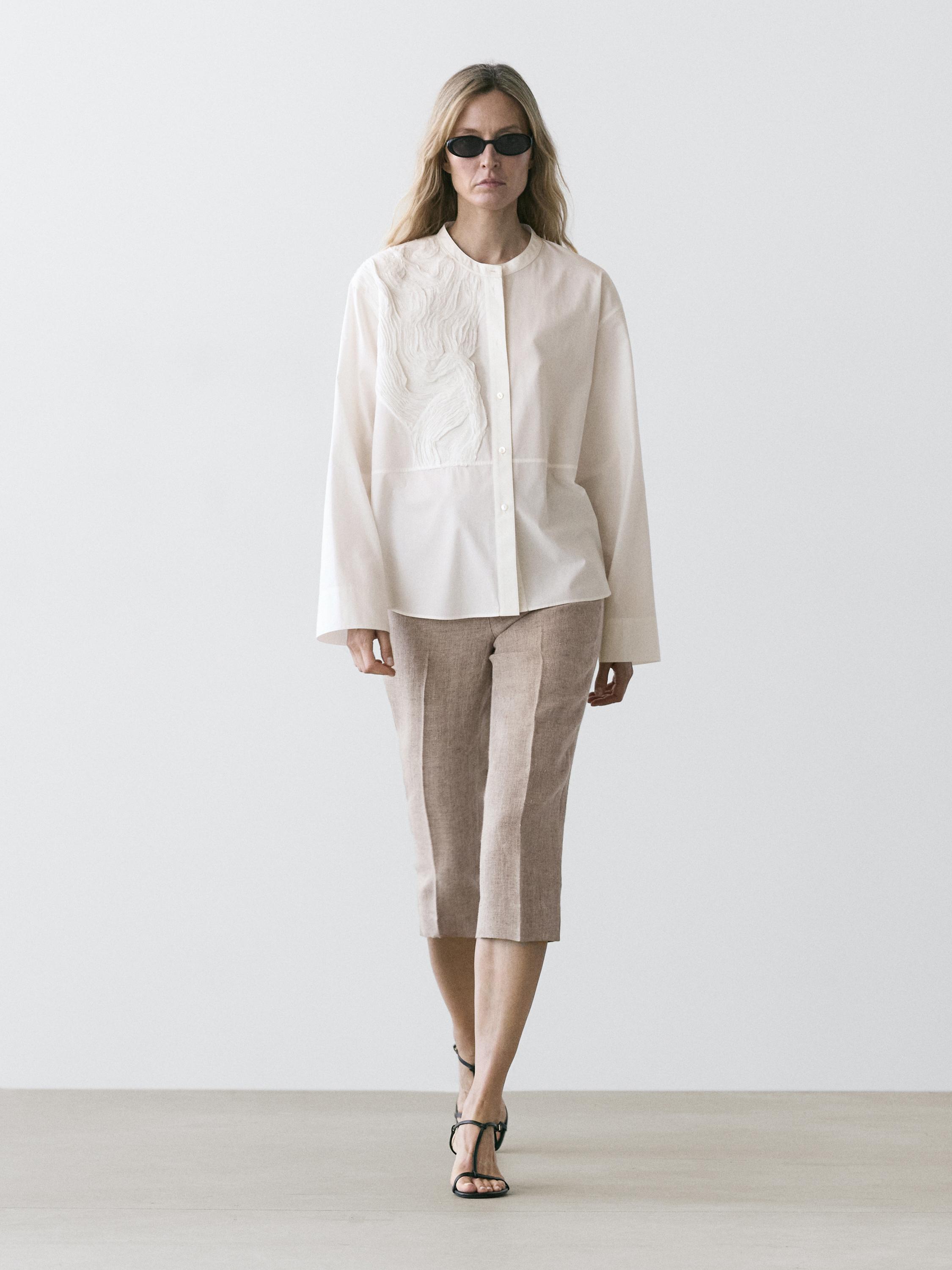 Göğüs işlemeli beyaz gömlek ve bej kapri pantolon takımı.