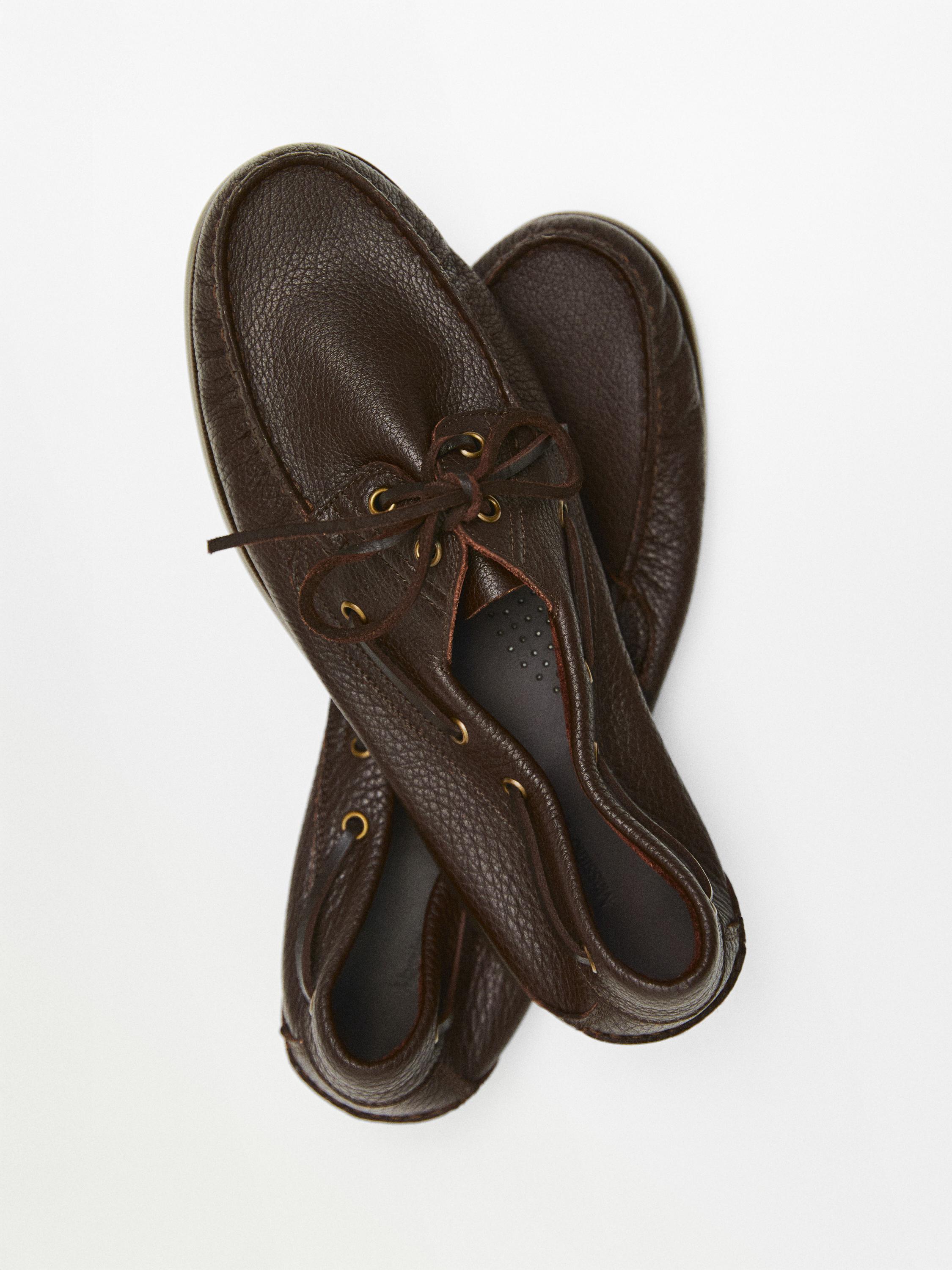 Vista superior de náuticos marrones con cordones y ojales metálicos.