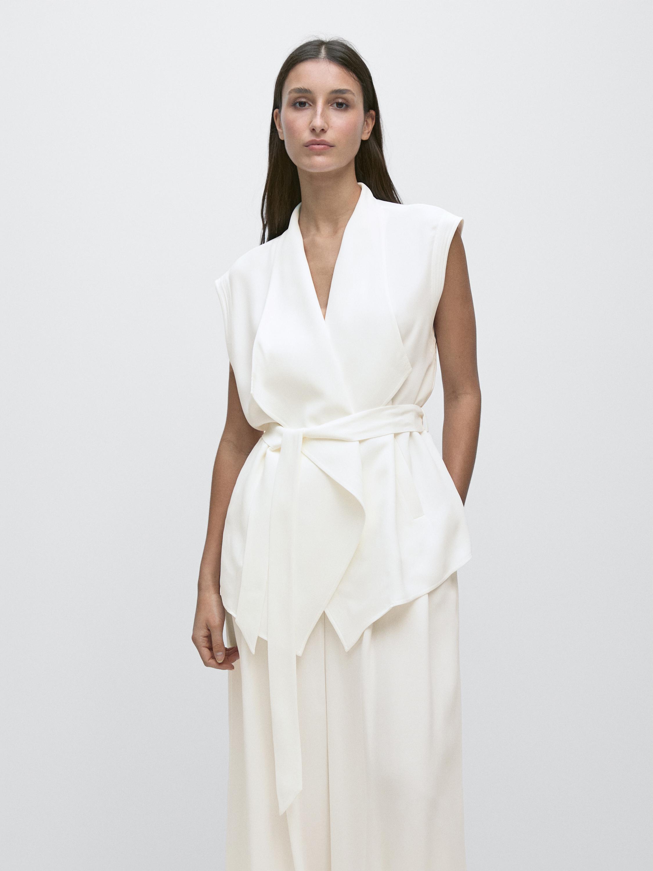 Set rompi putih pudar tanpa lengan dengan ikat pinggang simpul dan celana yang serasi.