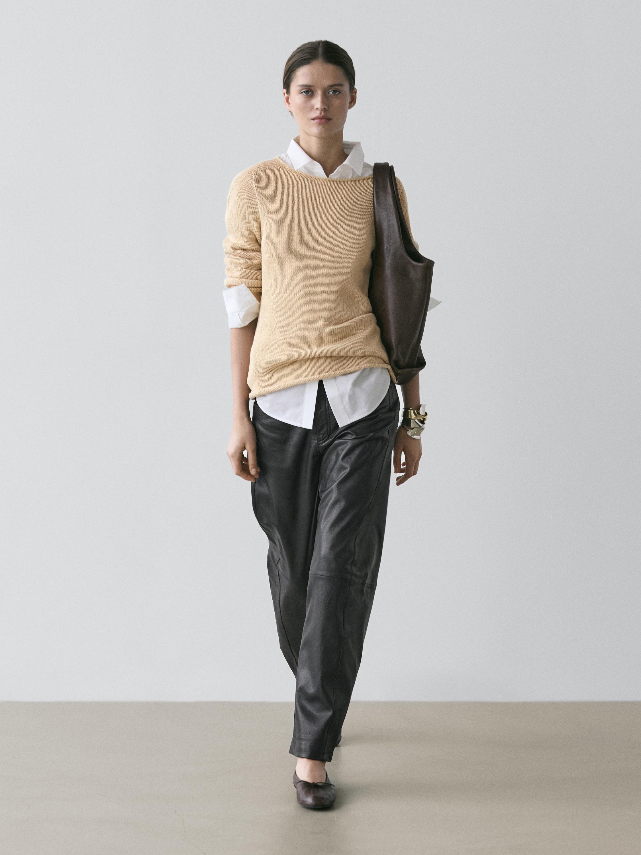 Conjunto de camisola milho, camisa branca e calças escuras.