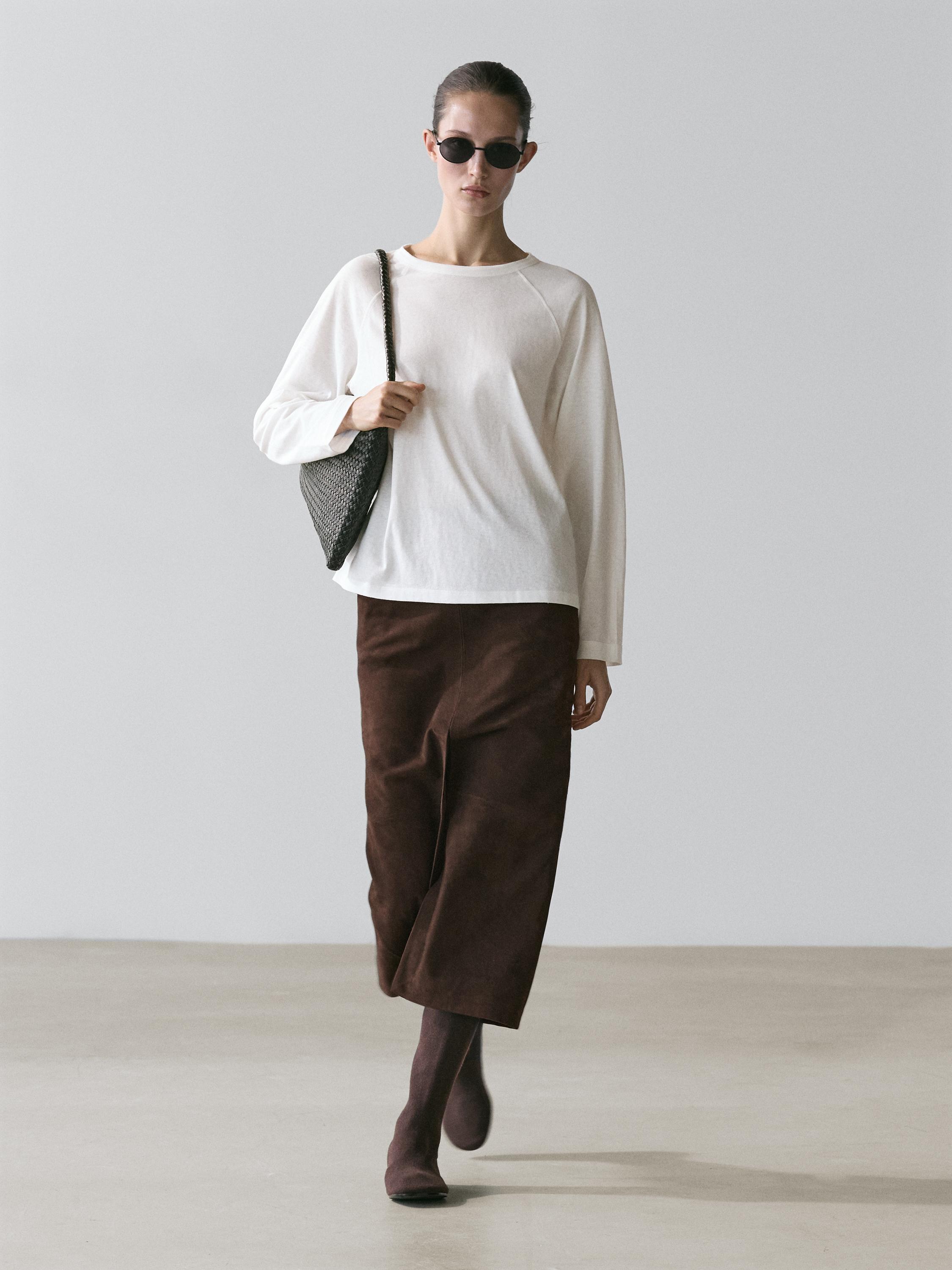 Ensemble composé d'un t-shirt blanc à manches longues et d'un pantalon marron large arrivant à la cheville.