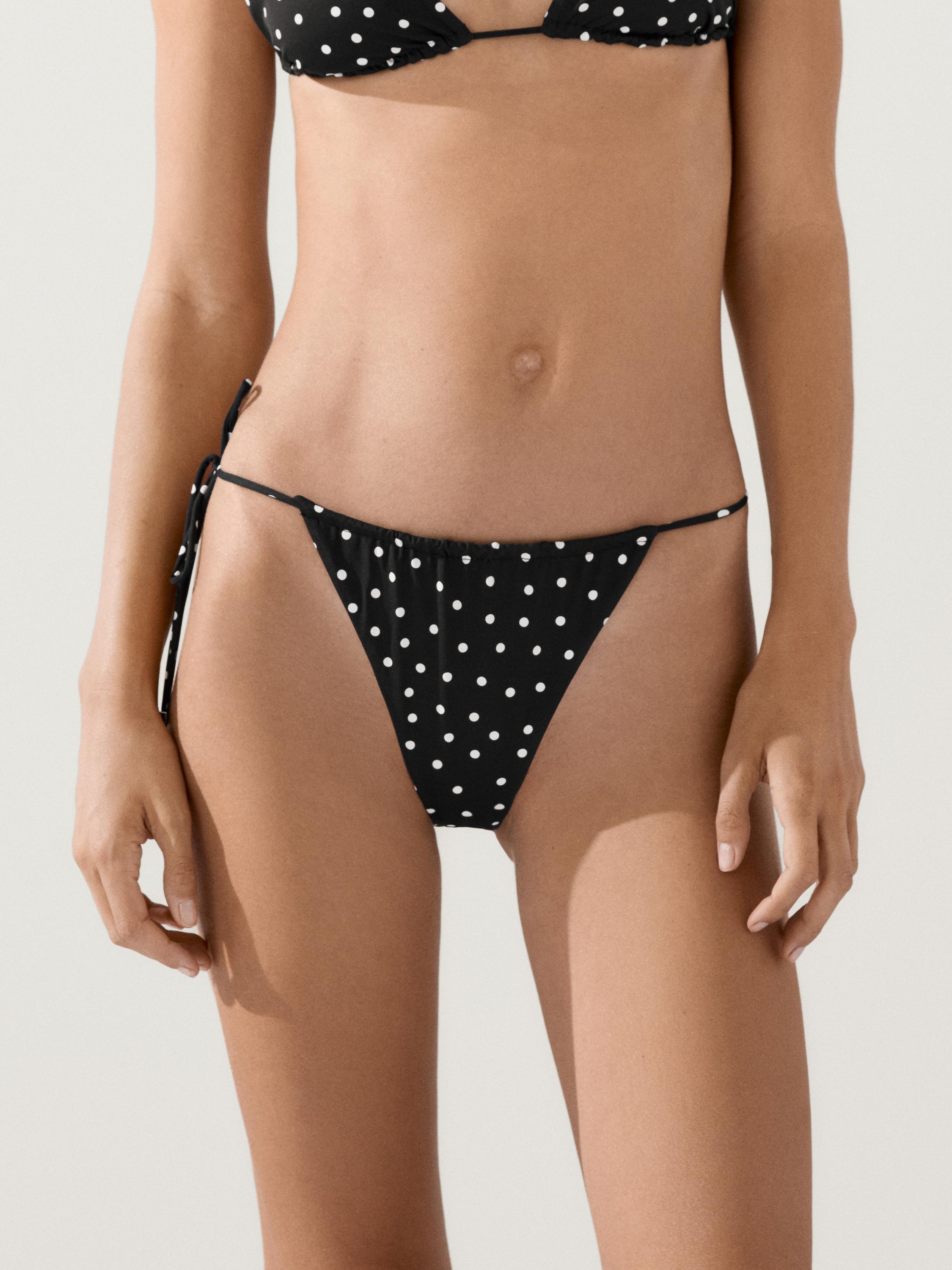 "Primer plano de braguita de bikini negra con estampado de lunares blancos y lazos laterales."