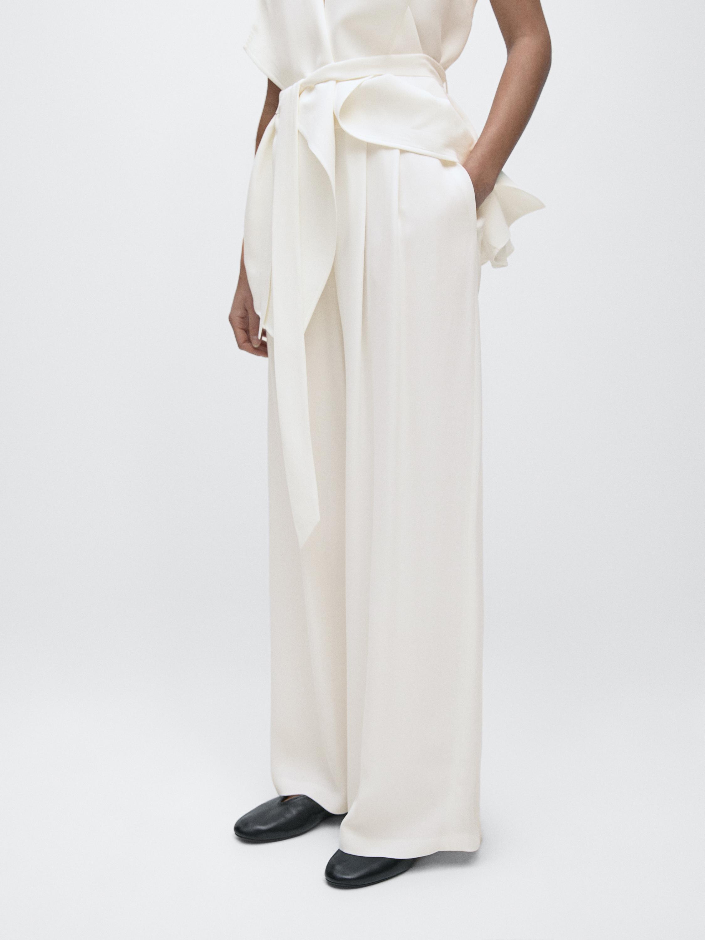 Potongan tengah celana putih tulang dengan ikat pinggang lebar dan saku samping.