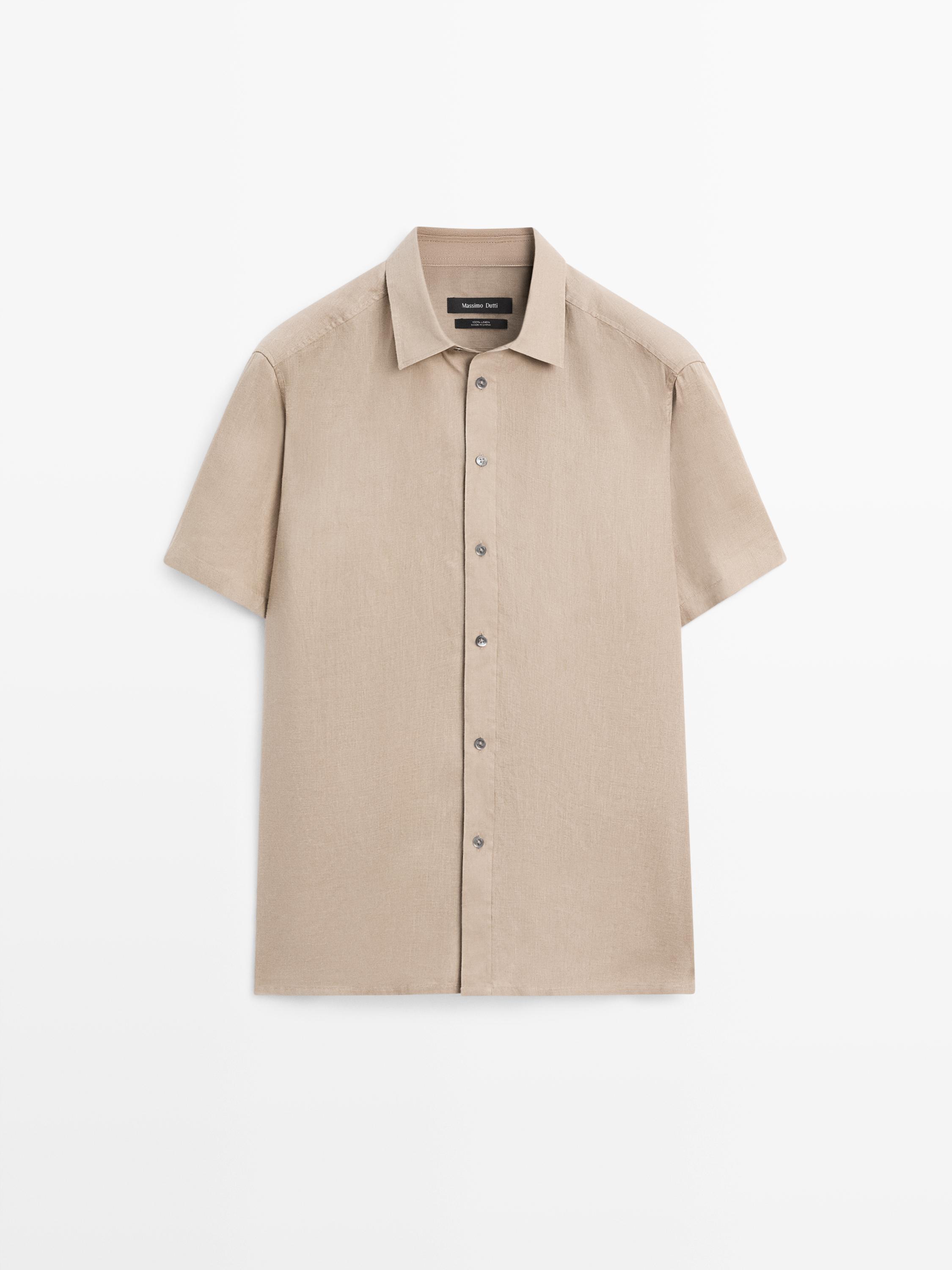 Vista frontal de camisa beige de manga corta con botonadura central y cuello clásico.