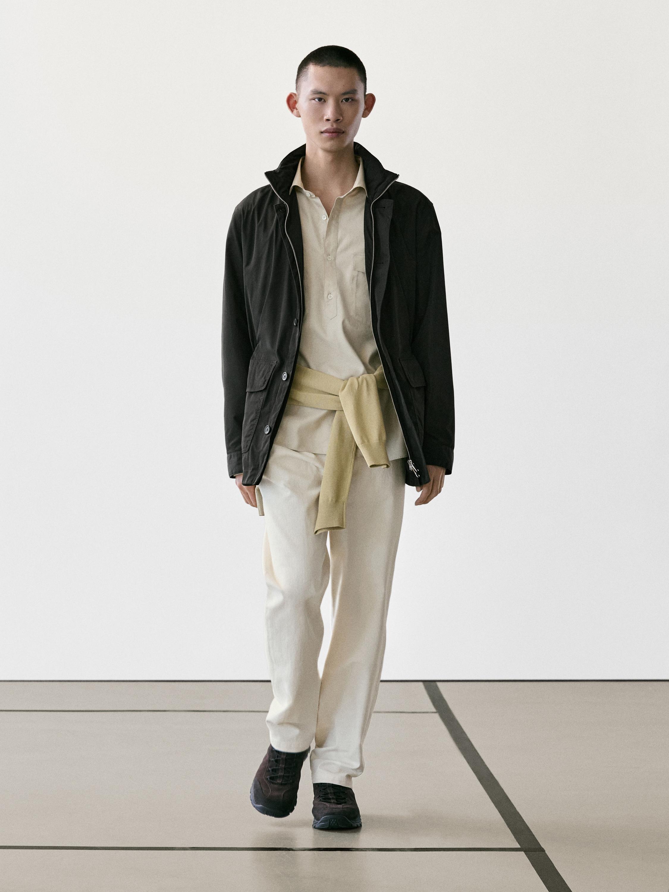 ชุดเสื้อแจ็คเก็ตสีดำมีกระเป๋า, เสื้อเชิ้ตสีเบจ, กางเกงสีอ่อน และเสื้อสเวตเตอร์สีเหลืองผูกเอว