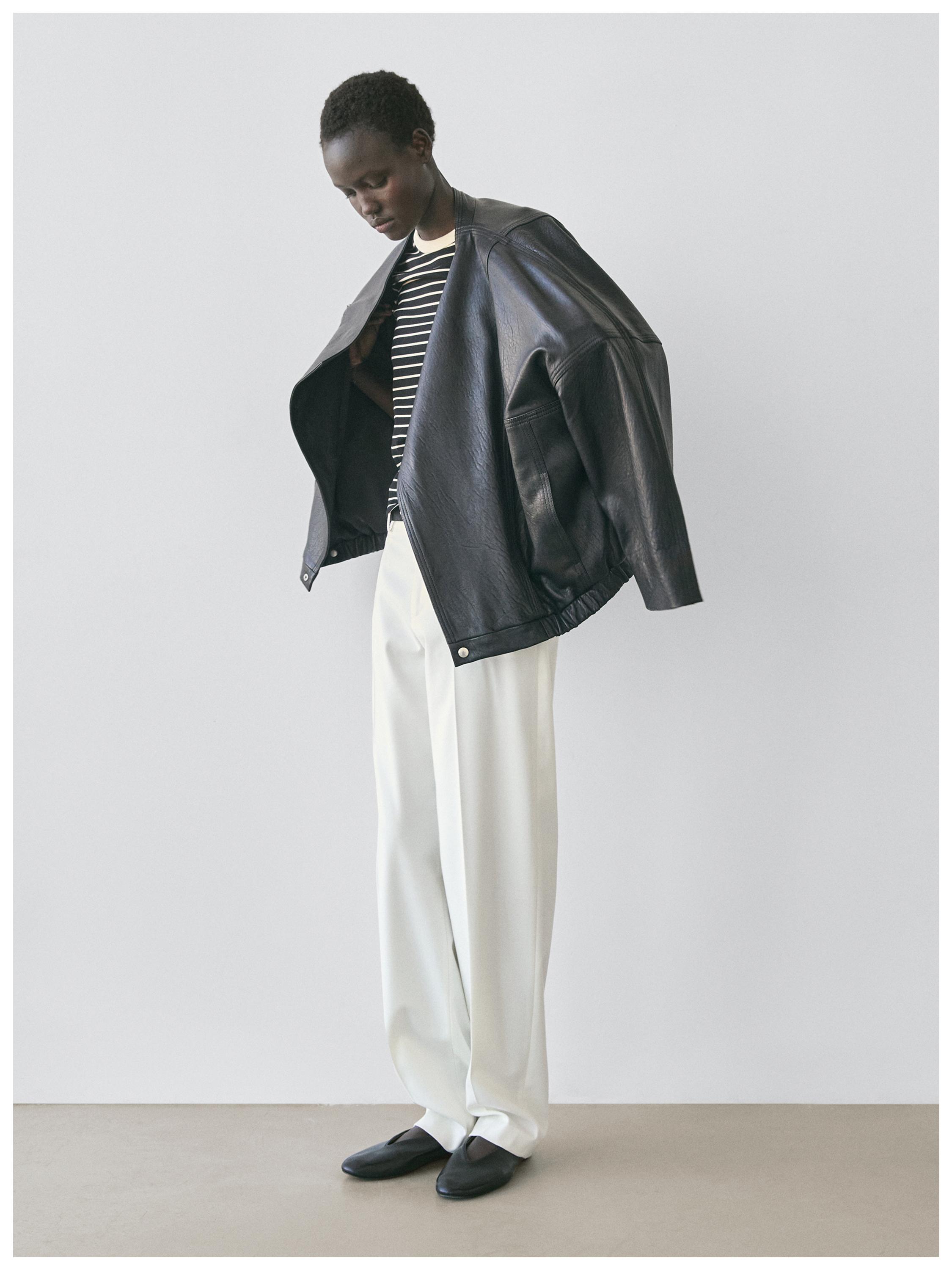 Black bomber jacket, black and white striped t-shirt, wide white pants, and black shoes.