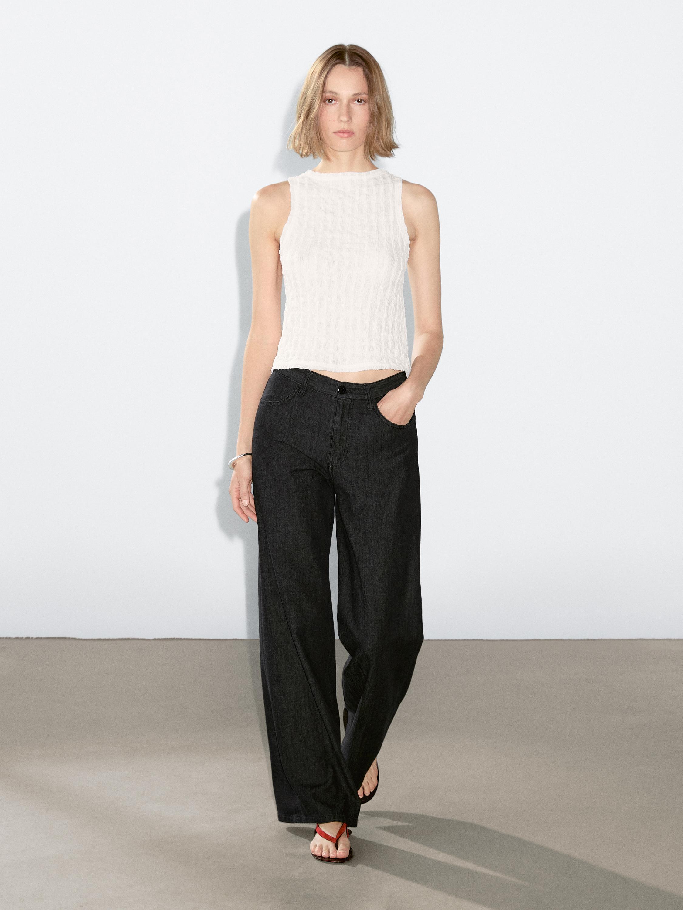 Ensemble jean gris foncé à jambes larges et top blanc sans manches.