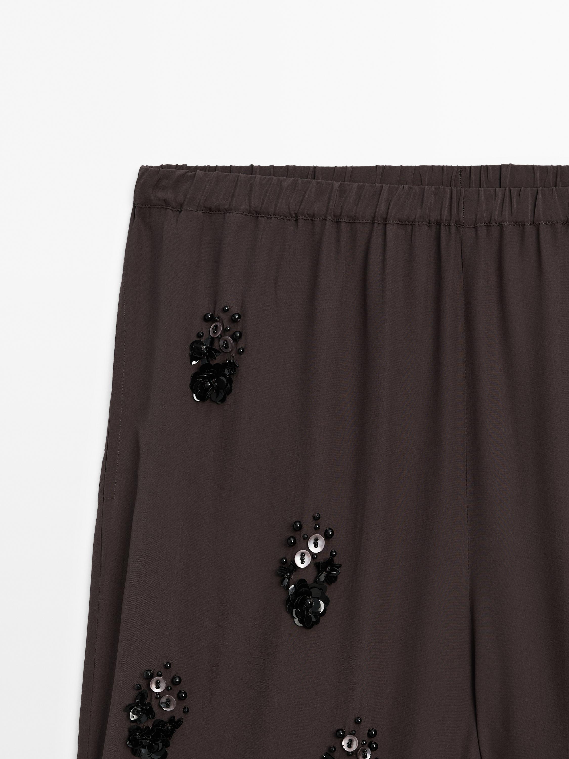 Flowing trousers with floral appliqués